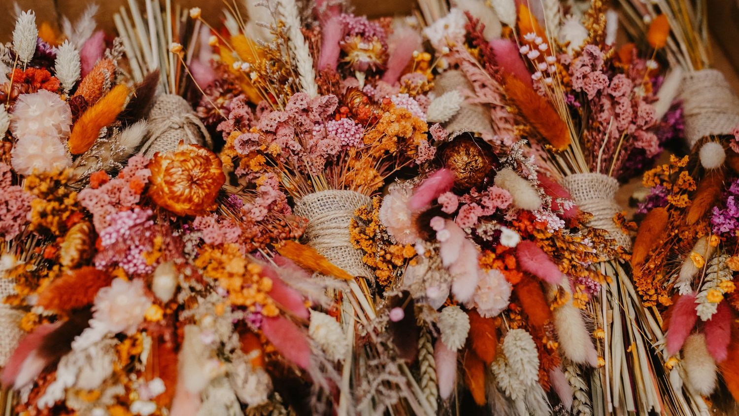 Artistic dried flower wedding decoration featuring pink and orange tones in a horizontal arrangement.