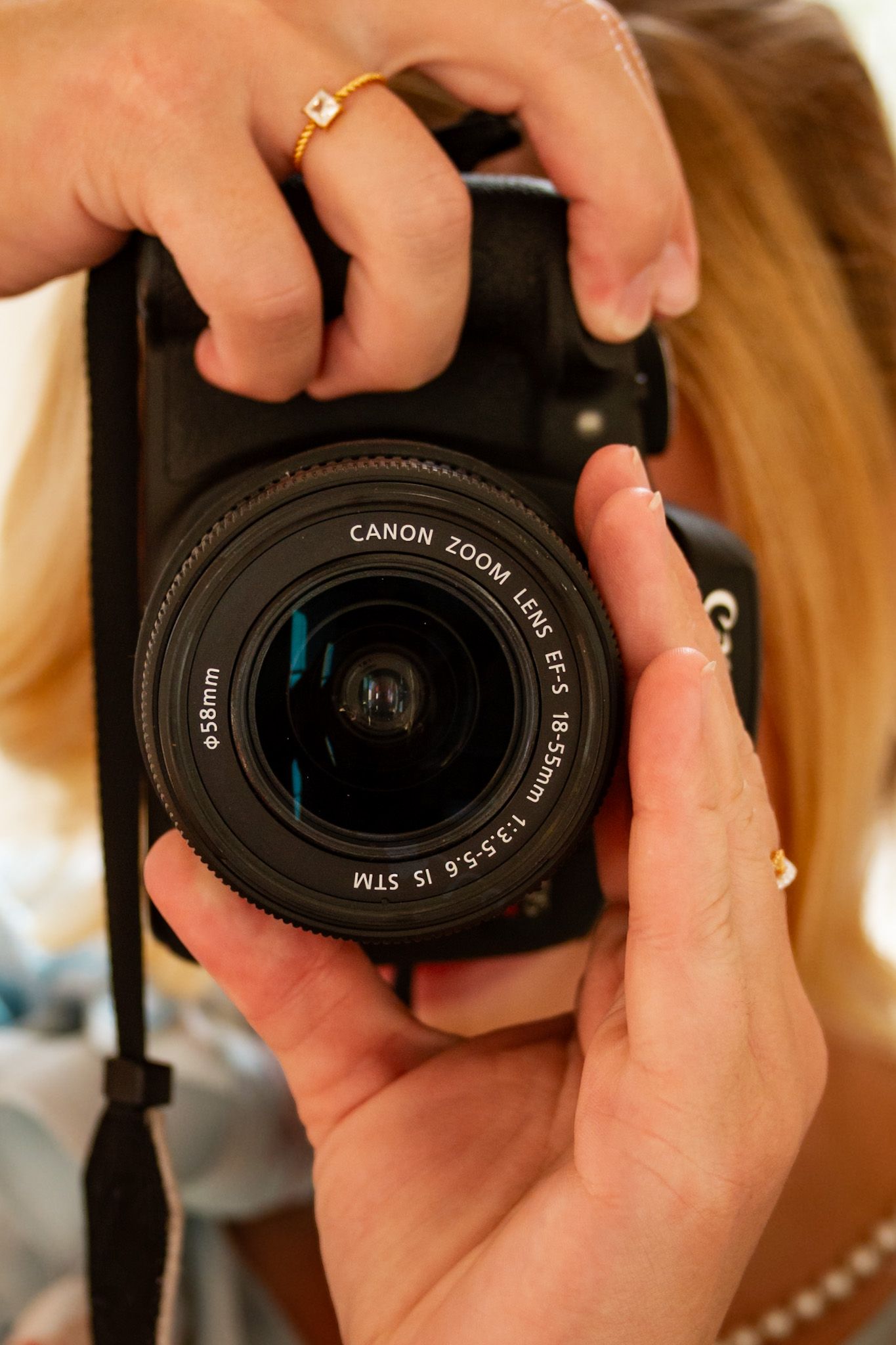 Close-up sequence of hands adjusting settings on a Canon camera lens against a warm-toned background.