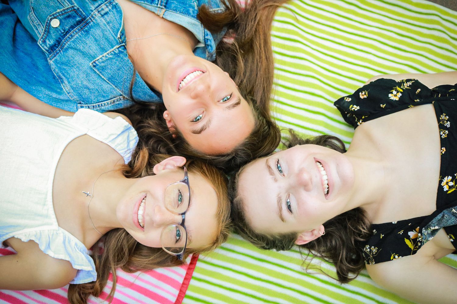 A series of five similar photos showing two people lying on a striped green blanket outdoors.