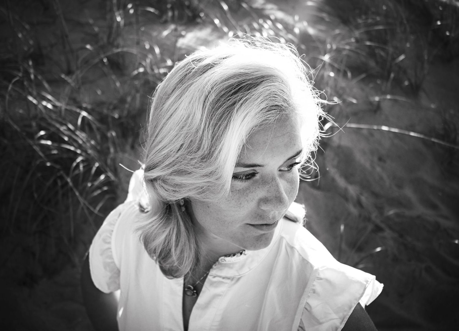 A series of black and white artistic portraits showing different angles of a woman with blonde hair in natural light.