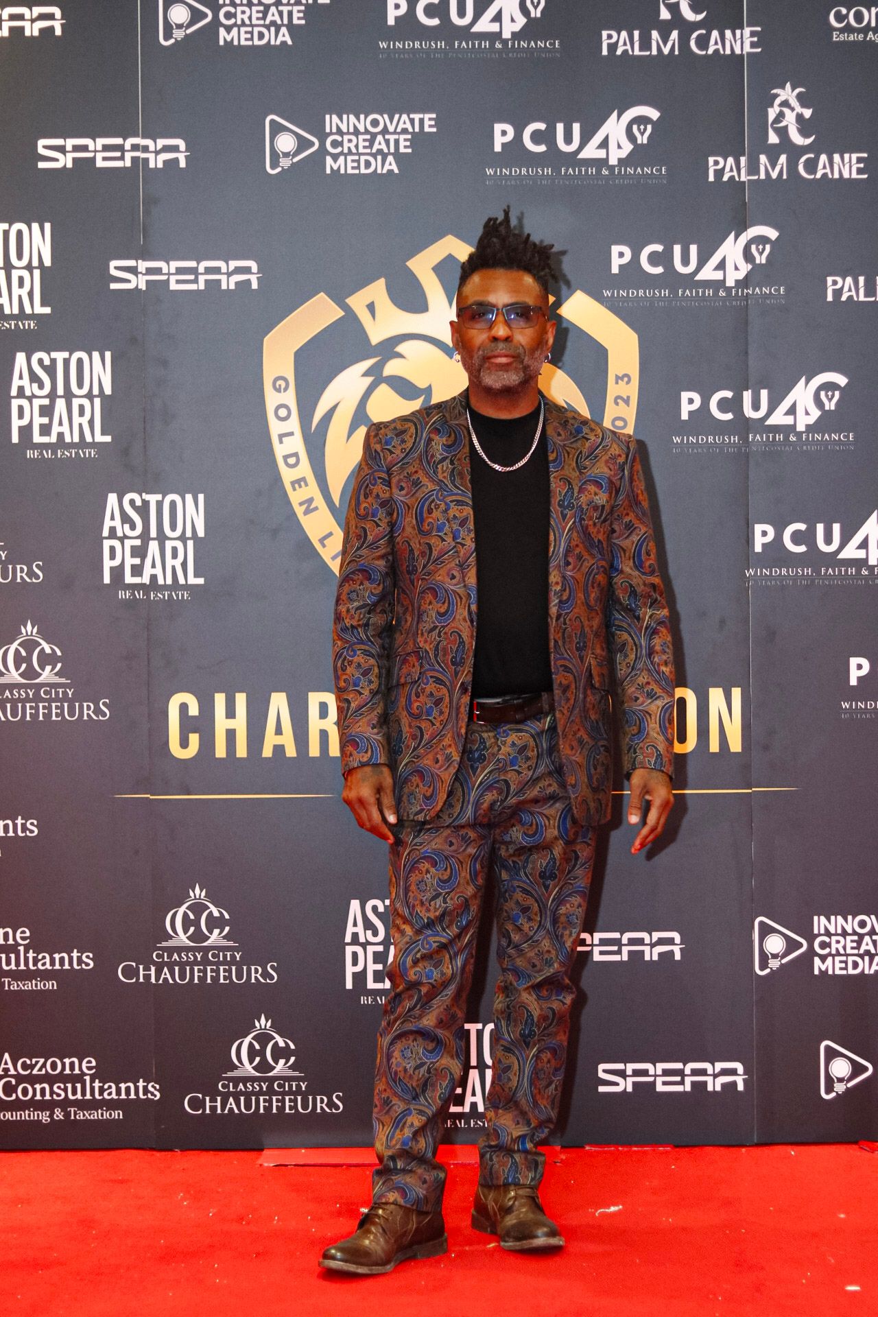 Attendees pose on red carpet in front of branded step-and-repeat wall.
