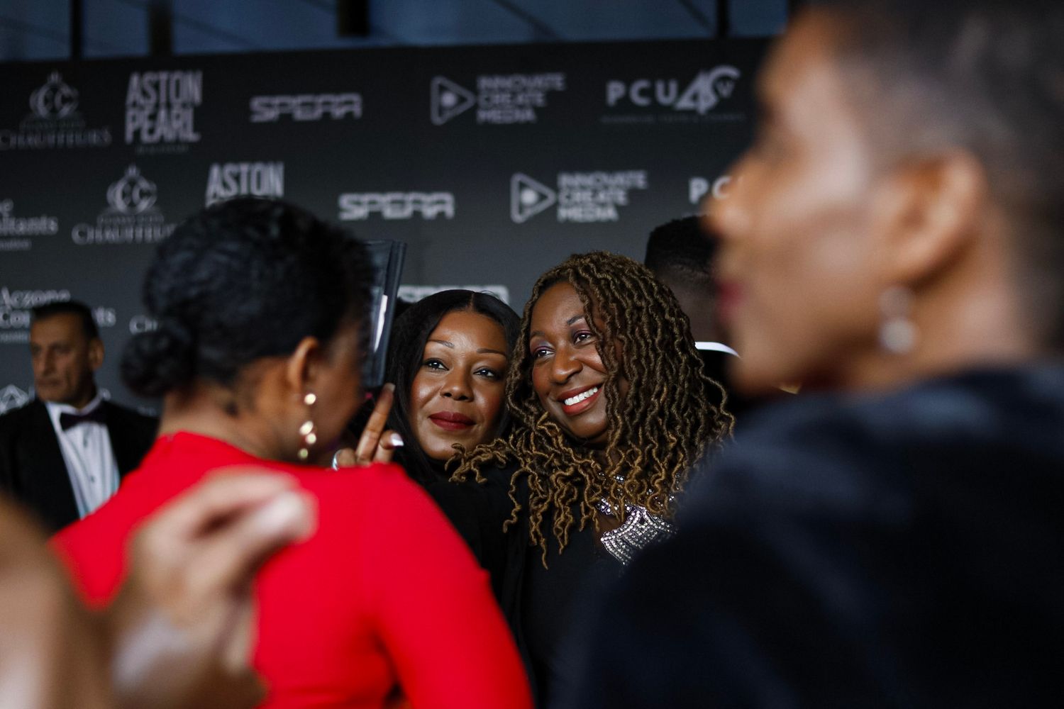 Guests mingling at a formal event with branded step-and-repeat backdrop.