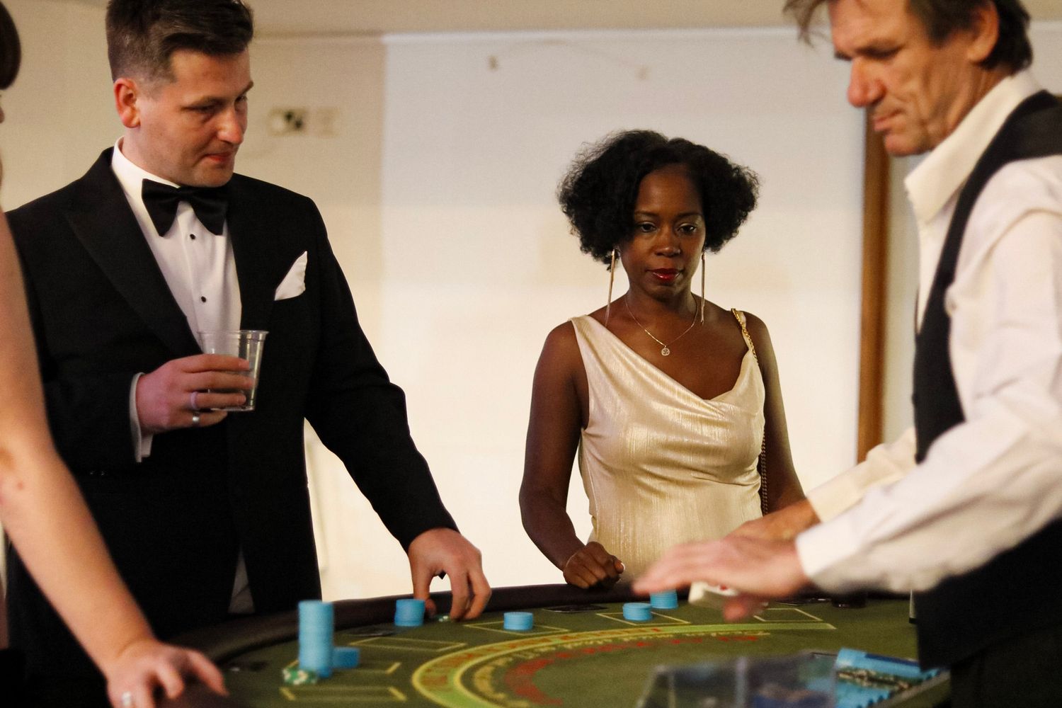 Guests playing at a casino table with a dealer in formal attire during an elegant event.
