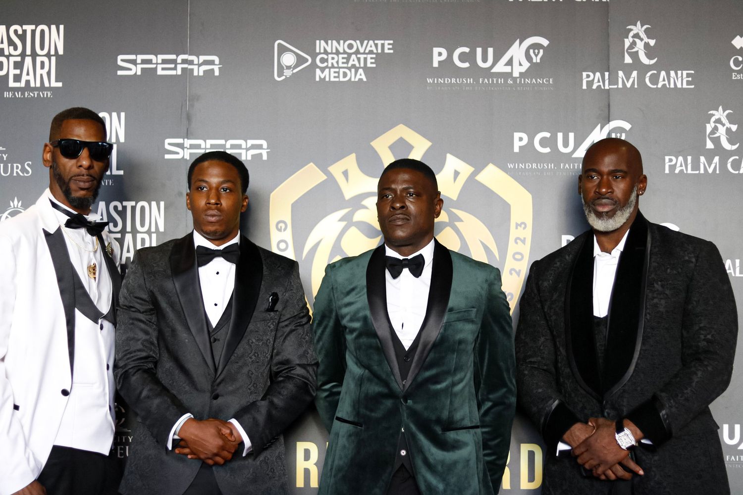 Group photo of attendees in formal suits at an entertainment industry event.