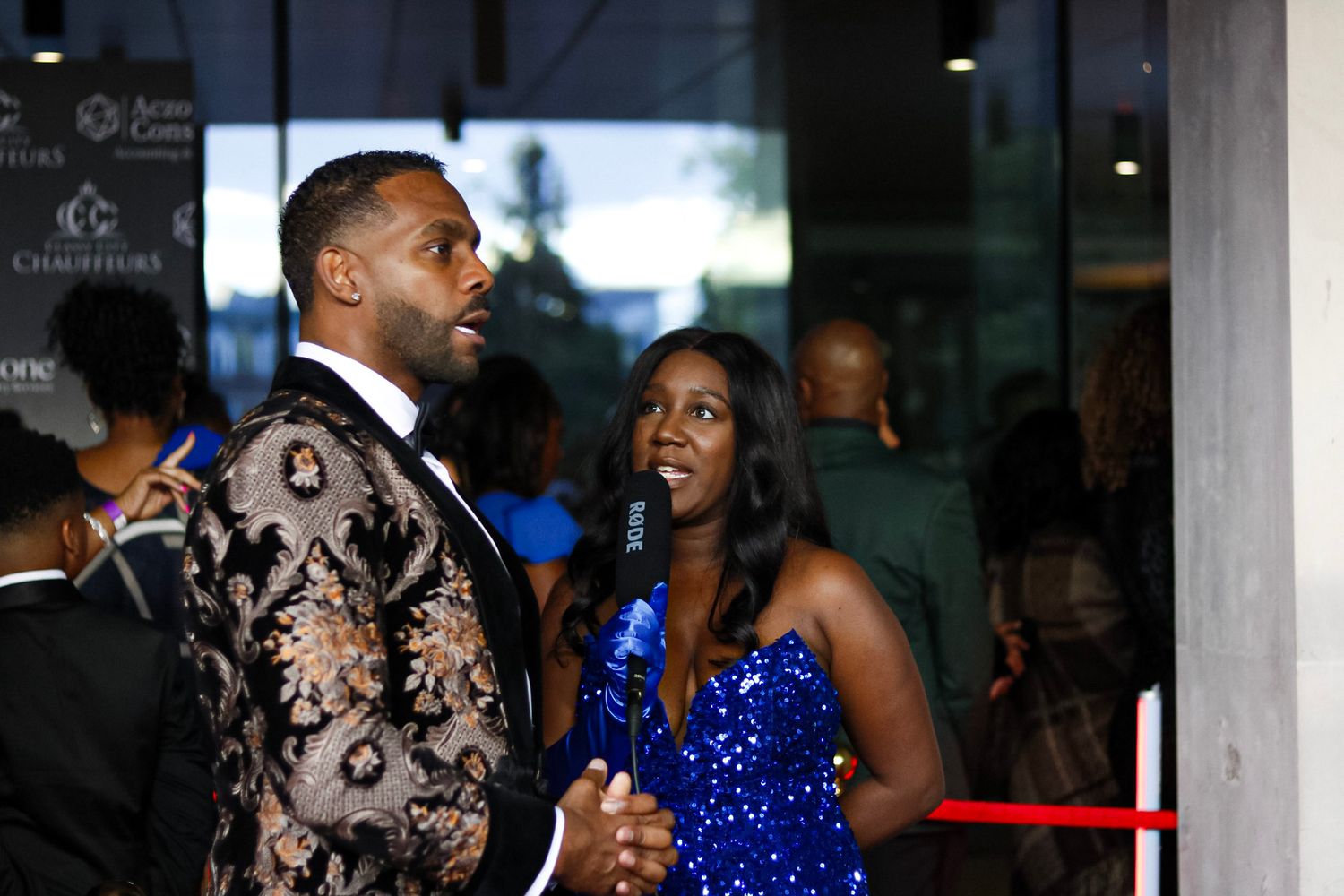Performers in formal attire interact on stage at an elegant awards ceremony.