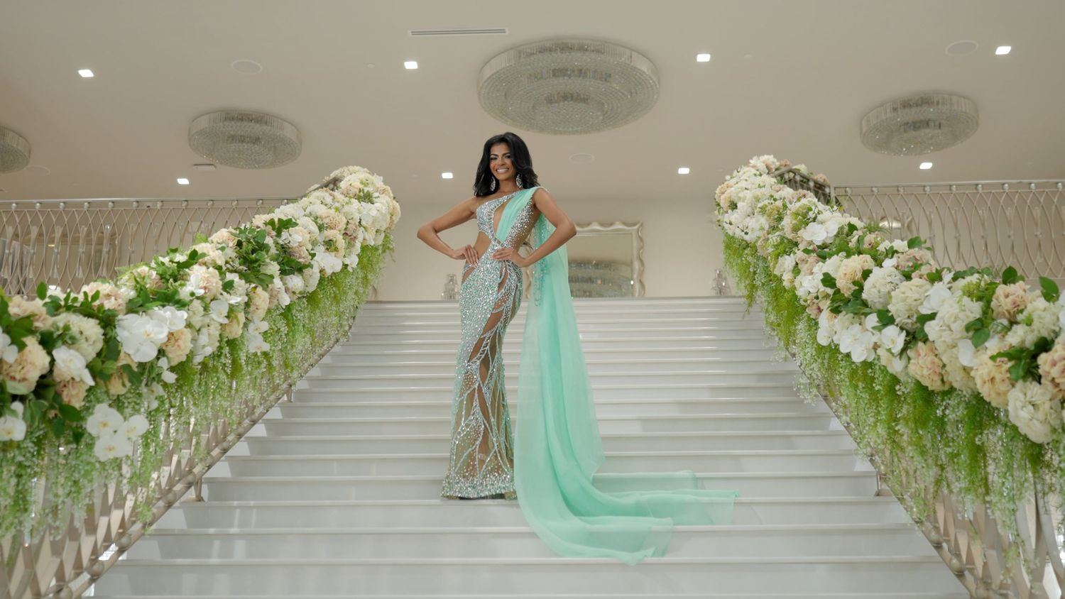 Elegant wedding venue decorated with white floral arrangements and mint green accents along a grand staircase.