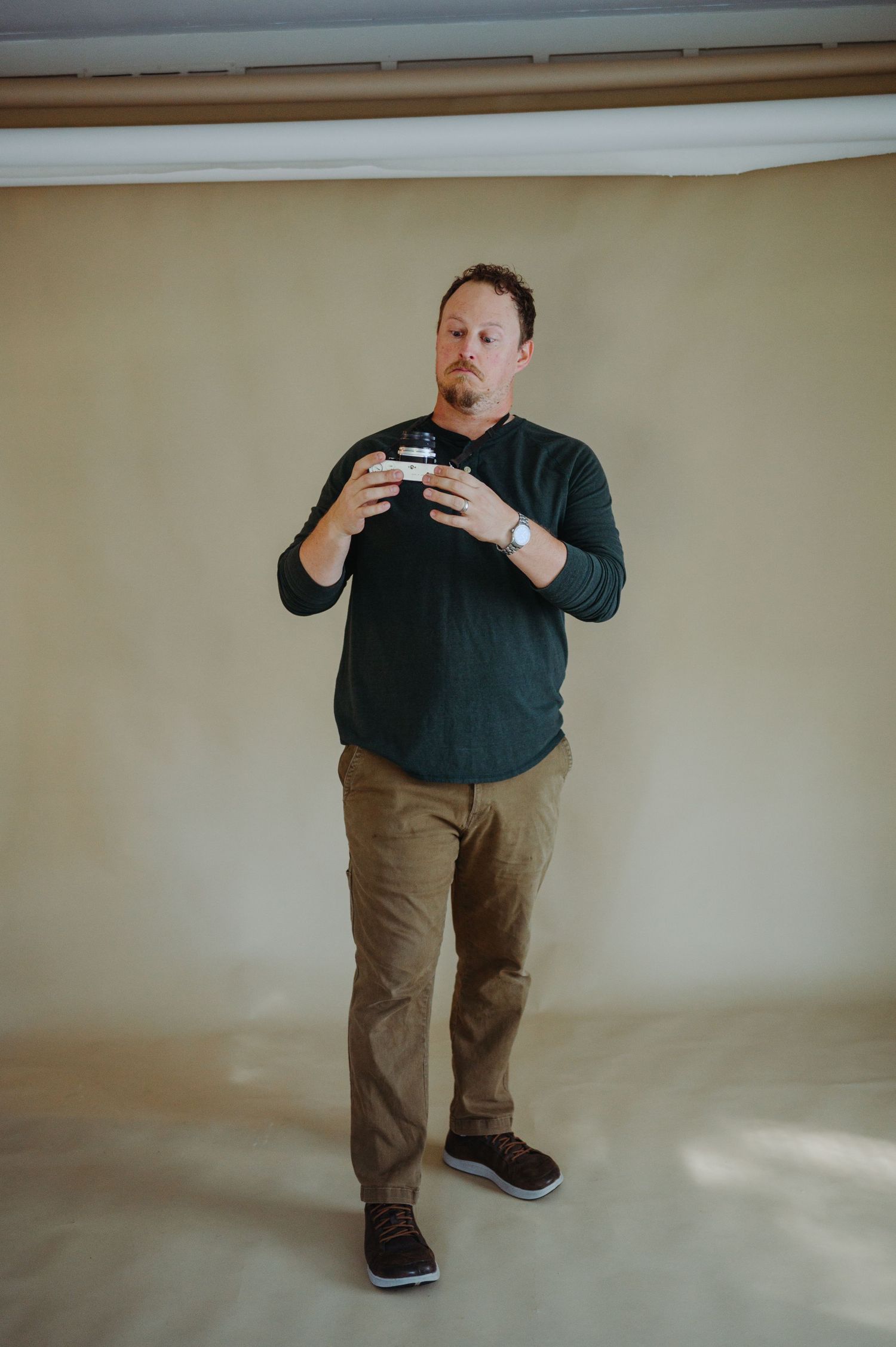 A person in a dark sweater and khaki pants demonstrates a series of poses against a beige wall.