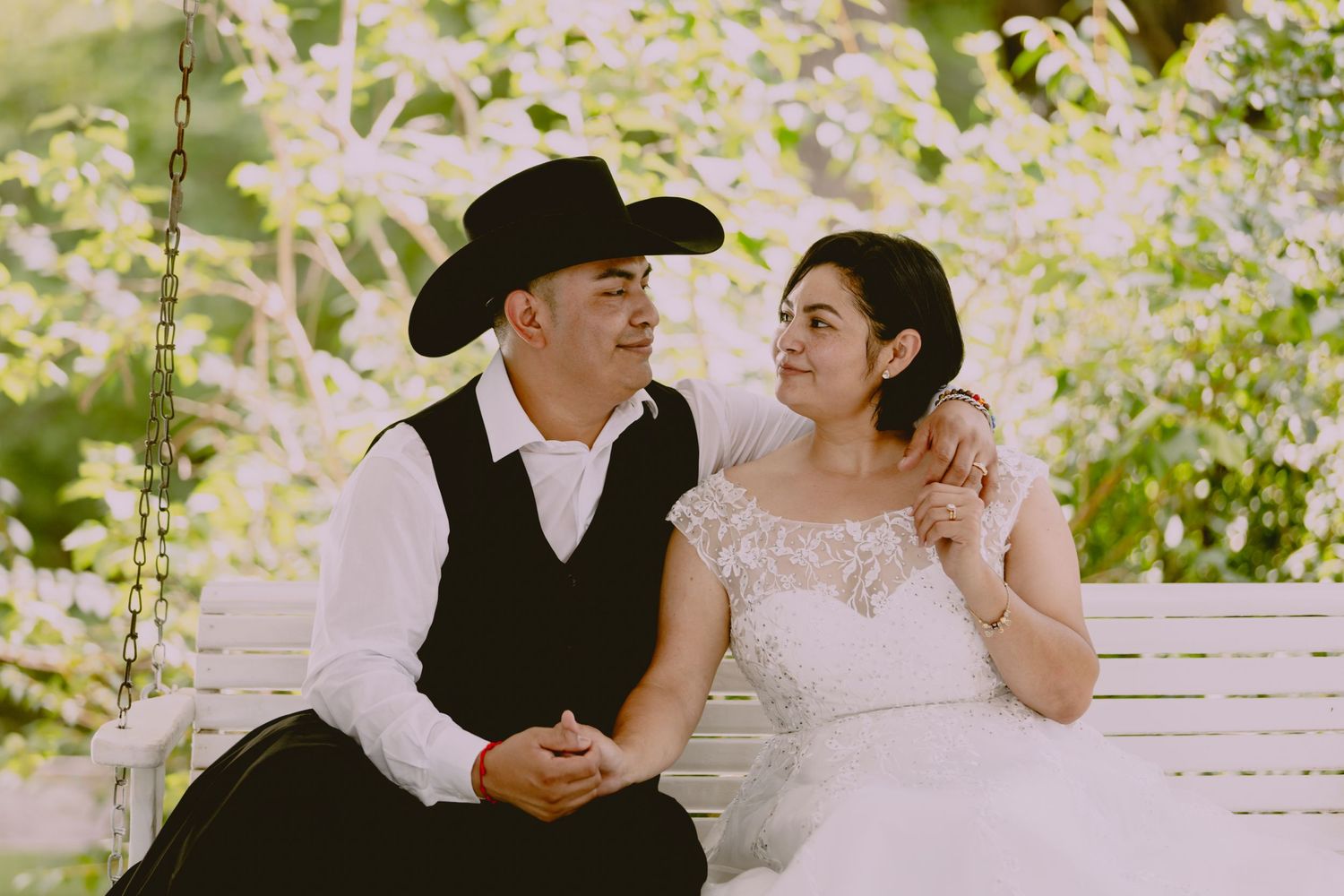 A couple shares intimate moments on a classic white porch with natural lighting.
