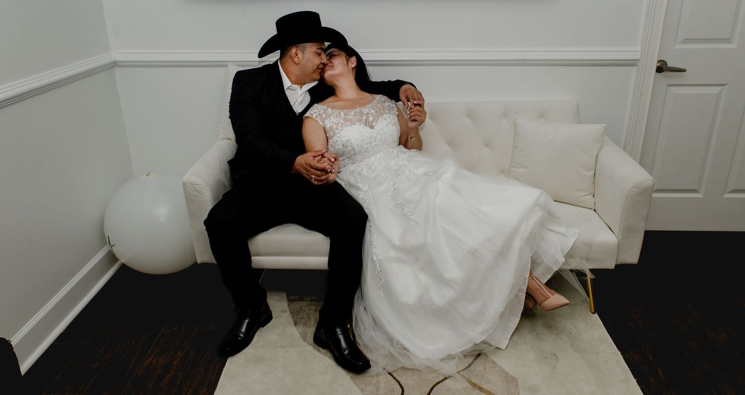 A romantic wedding moment on a white couch with elegant decor and balloons.