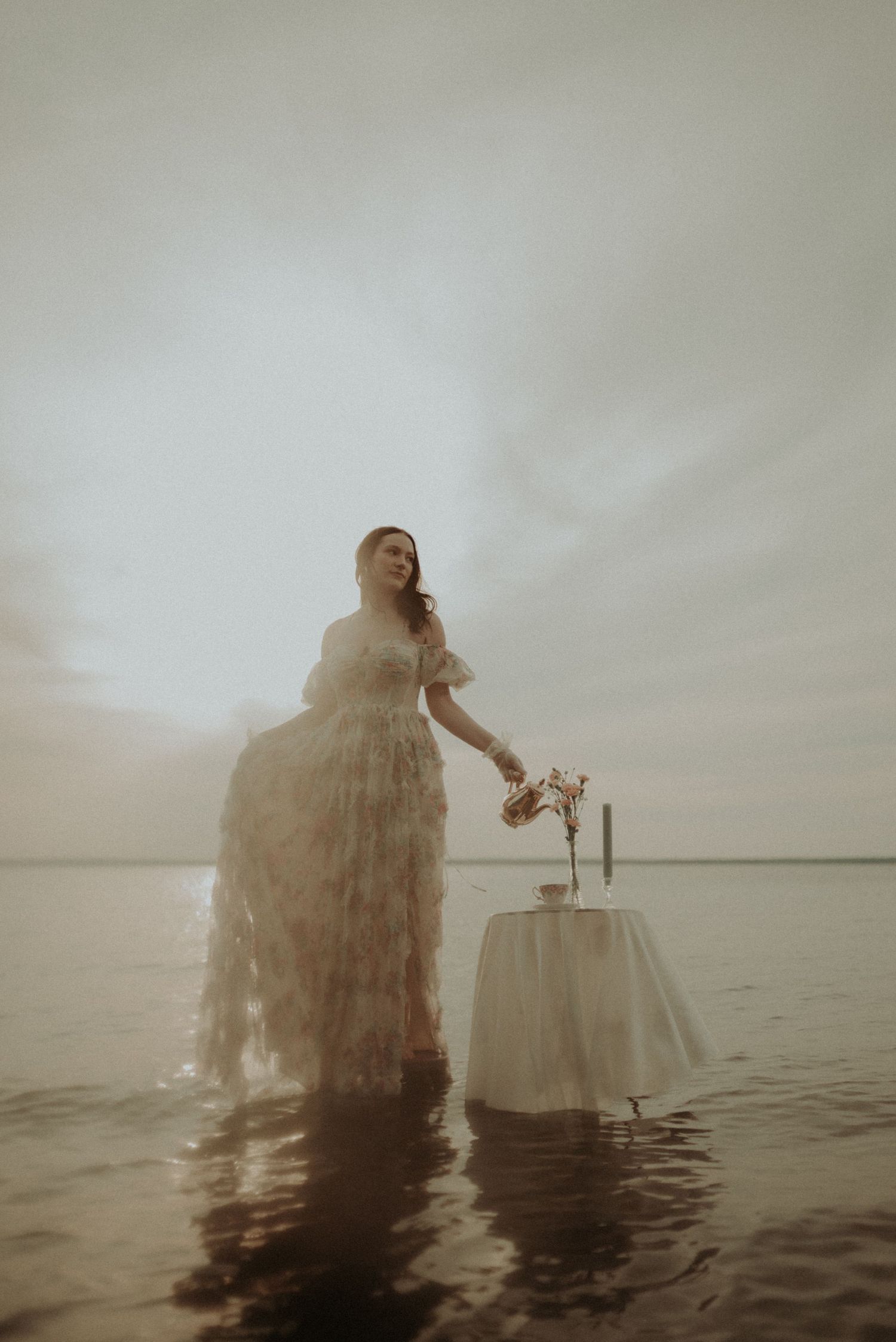 Ethereal artistic portrait in water with flowing dress and misty atmosphere.