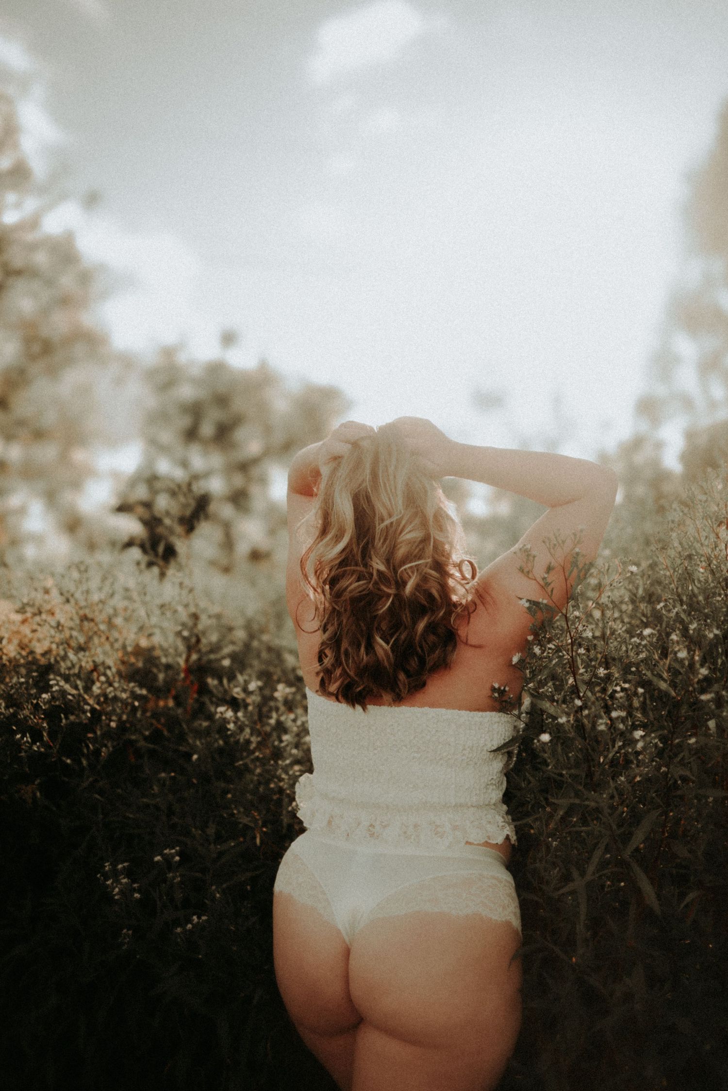 Artistic boudoir photography series showing silhouette against foliage in natural lighting.