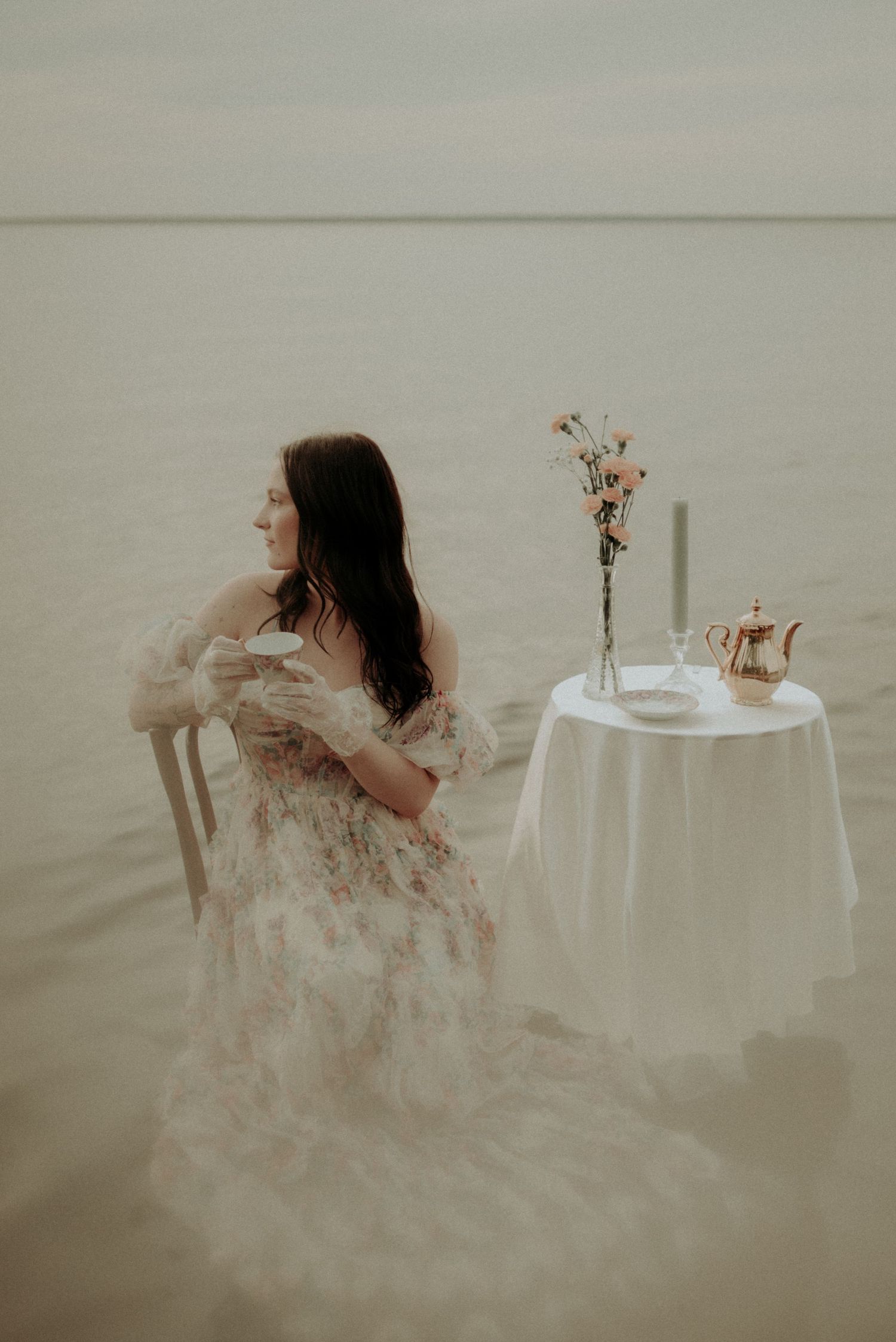 Dreamy water photography featuring white table setting and flowing dress in muted tones.