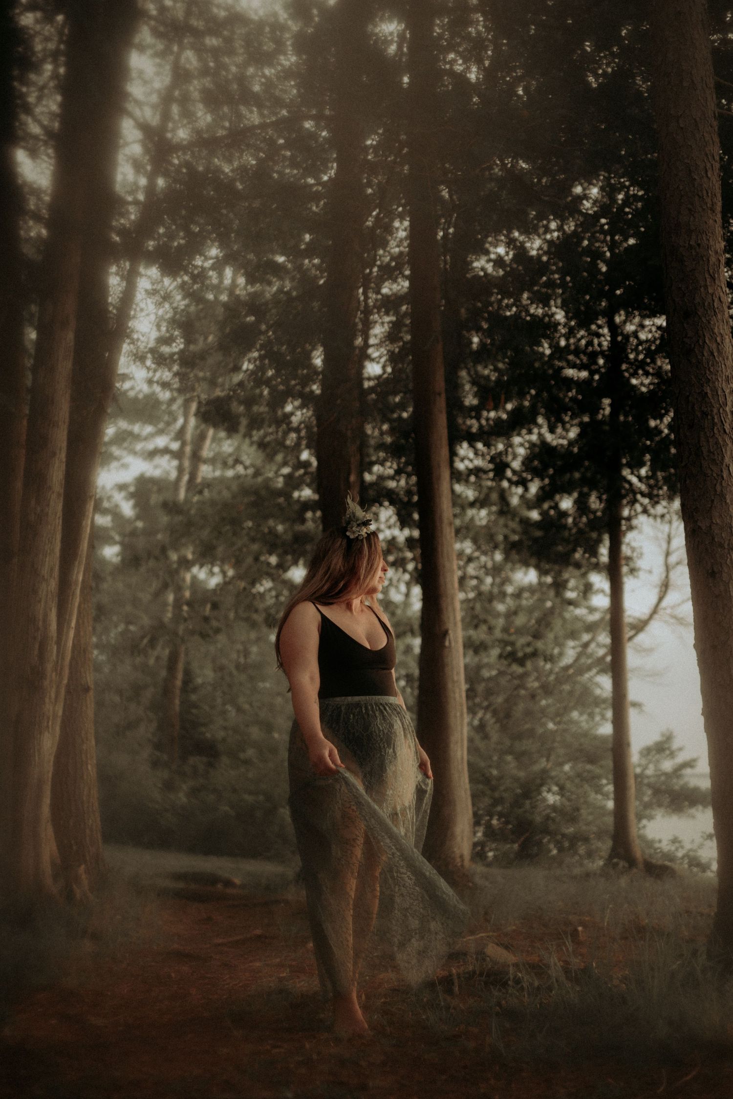 Atmospheric woodland portrait with misty lighting and ethereal dress movement.