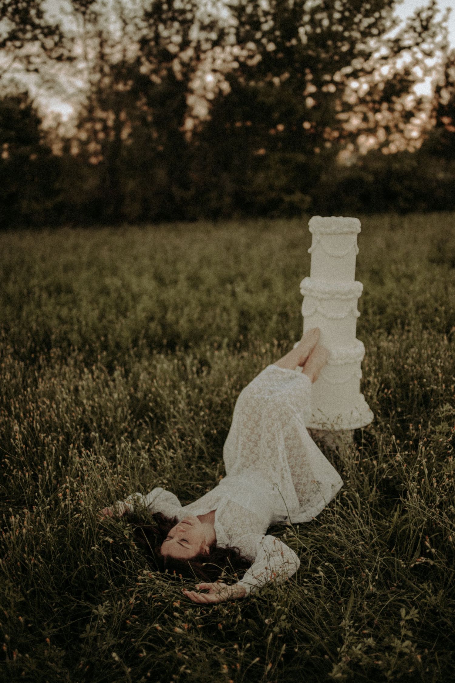A dreamy outdoor scene with a white lace dress flowing in a grassy meadow at sunset.
