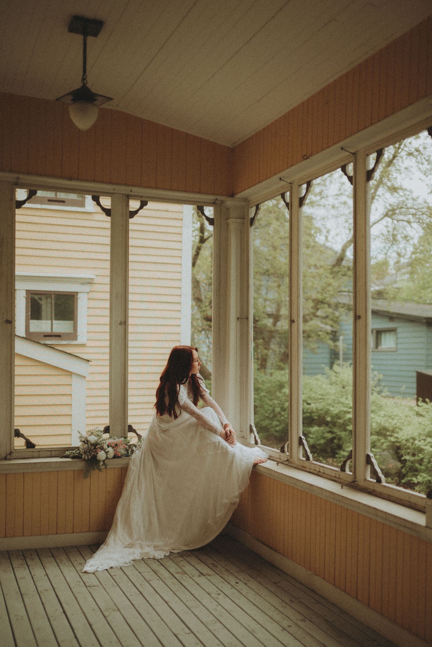 A dreamy bridal portrait on a wraparound porch with wooden details and natural lighting.