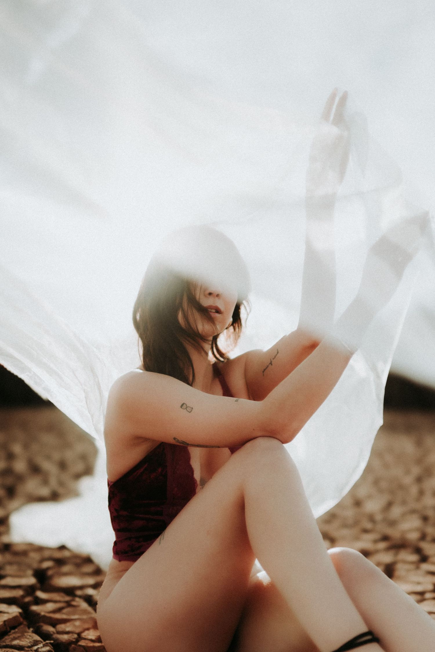 Artistic photo series showing a figure draped in flowing white fabric against a textured brown background.
