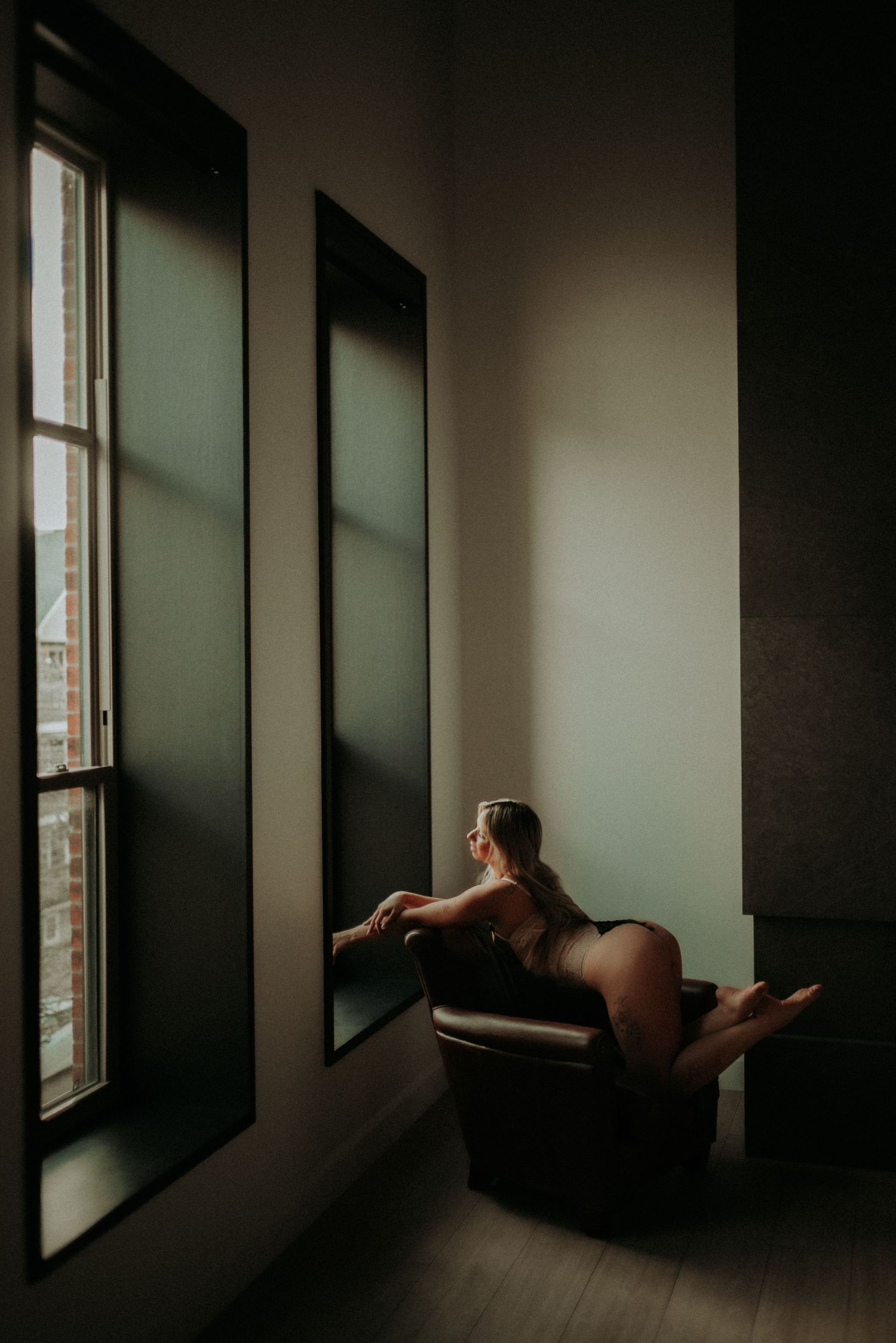Artistic dark room interior with dramatic window lighting and shadows on wooden floor.
