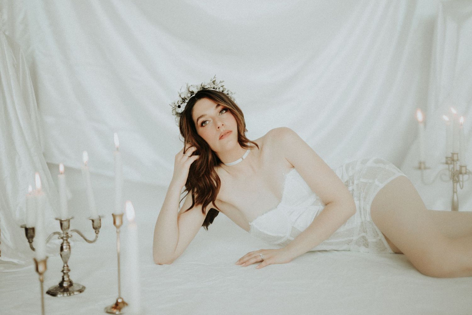 Elegant bridal boudoir photography series featuring soft white draping fabric and vintage candelabras.