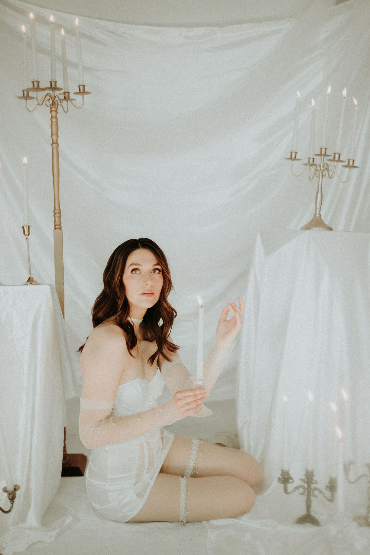 Artistic boudoir photography series featuring ethereal white drapes and vintage candelabras creating a dreamy atmosphere.