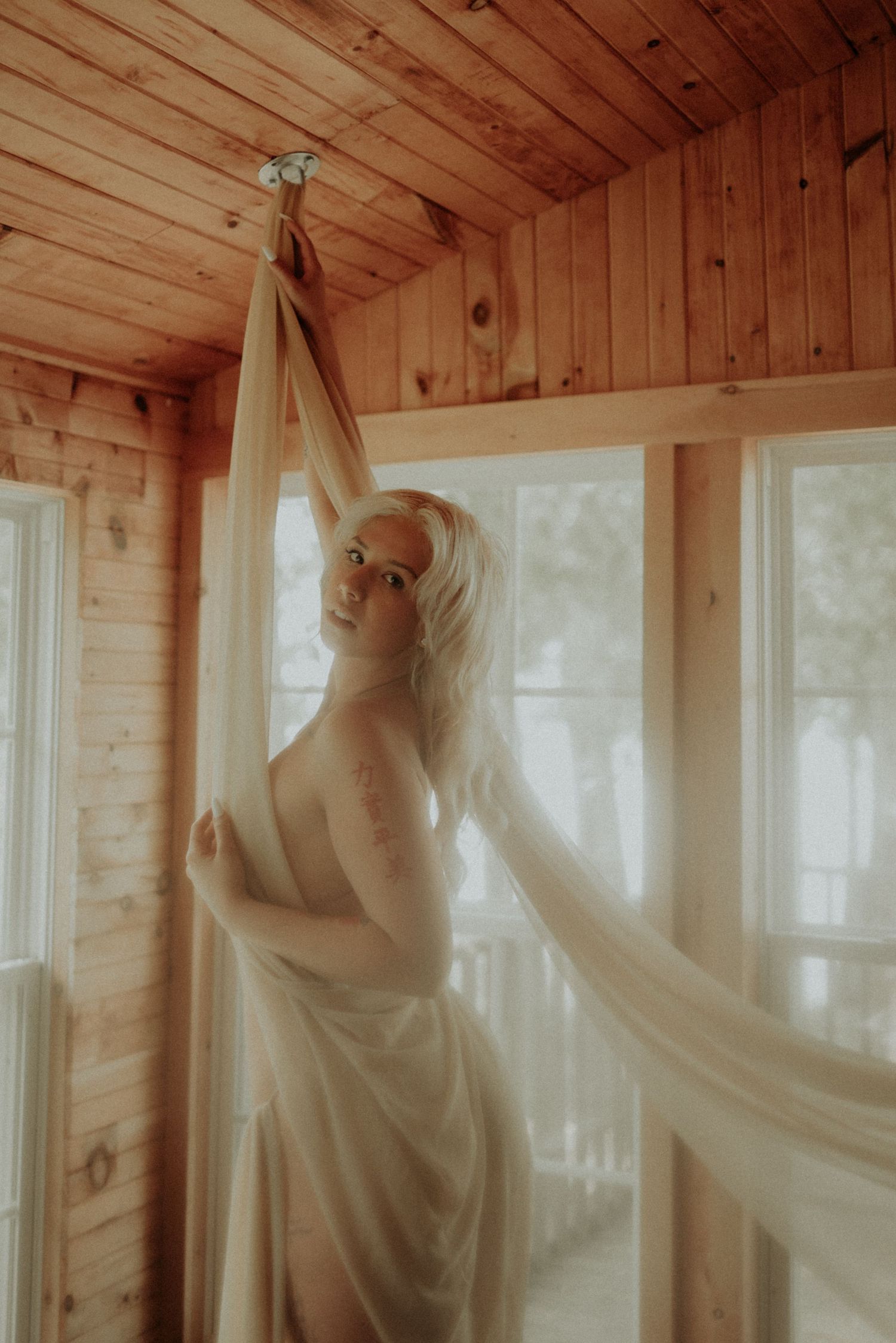 Soft, romantic photo series with billowing white fabric in sunlit cabin space.