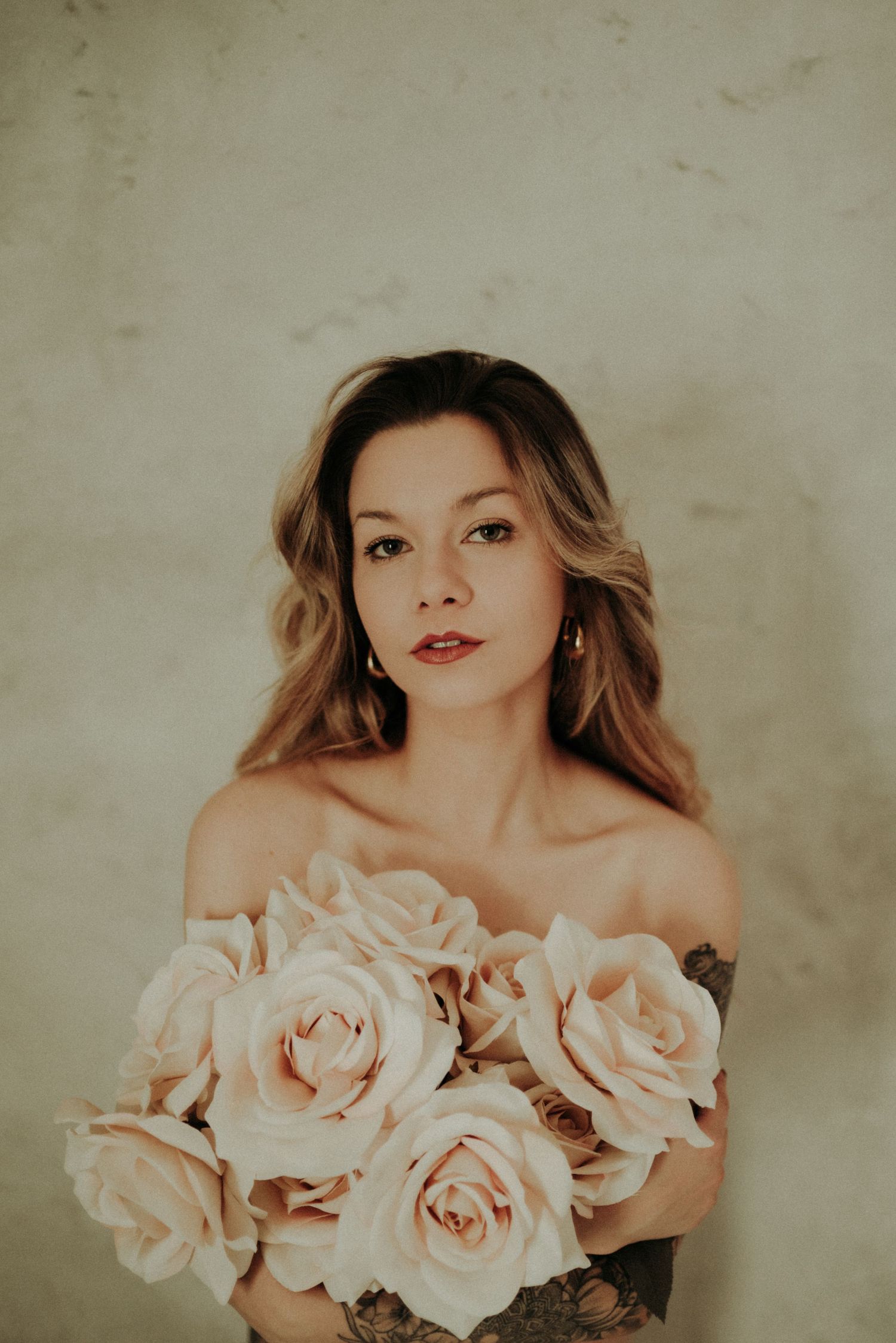 Dreamy portrait with pale blush roses in a vintage style featuring soft lighting and muted warm tones.