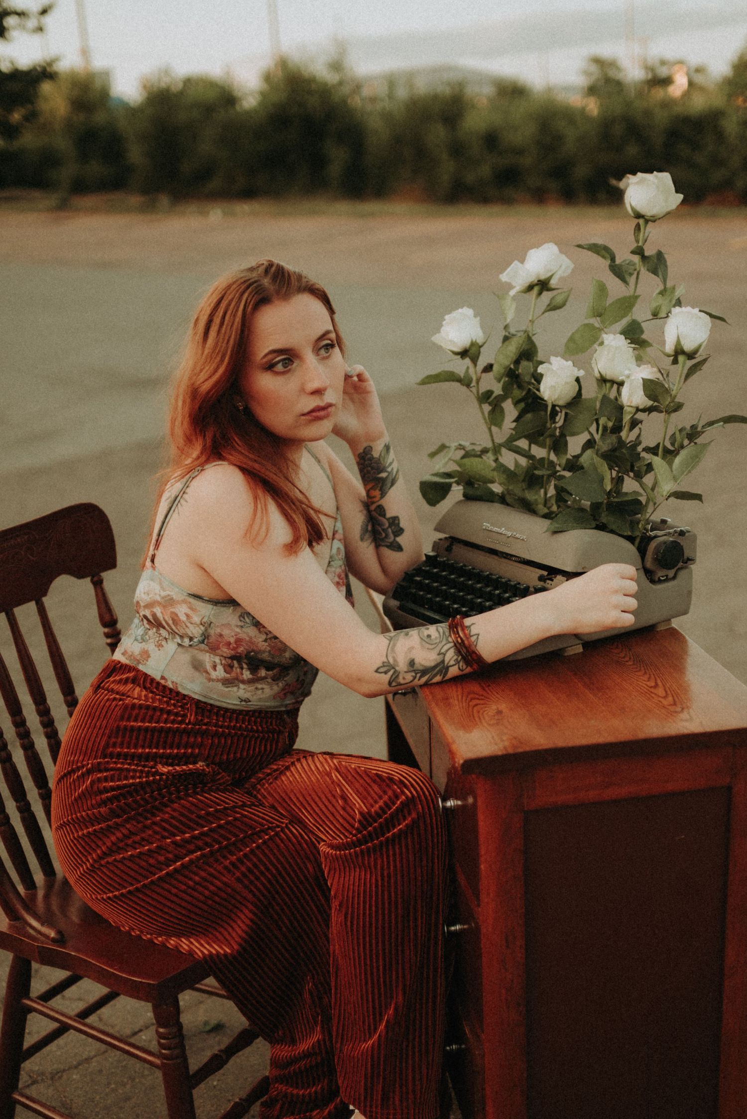 Nostalgic portrait with vintage typewriter and white roses in warm evening light.