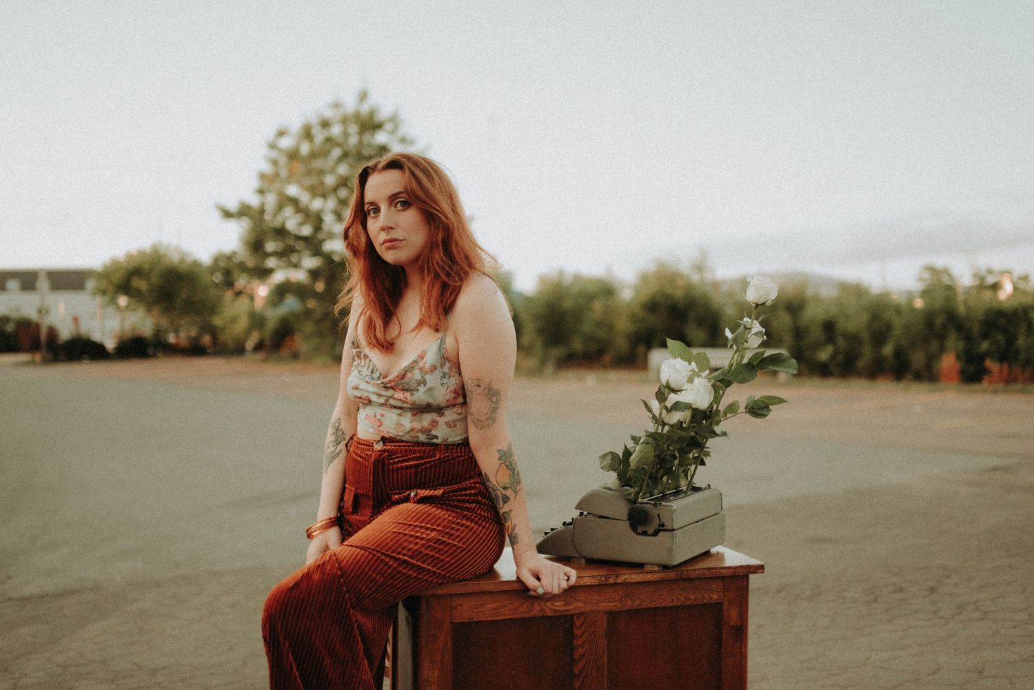 Vintage-inspired scene with antique desk, typewriter and white flowers at sunset.