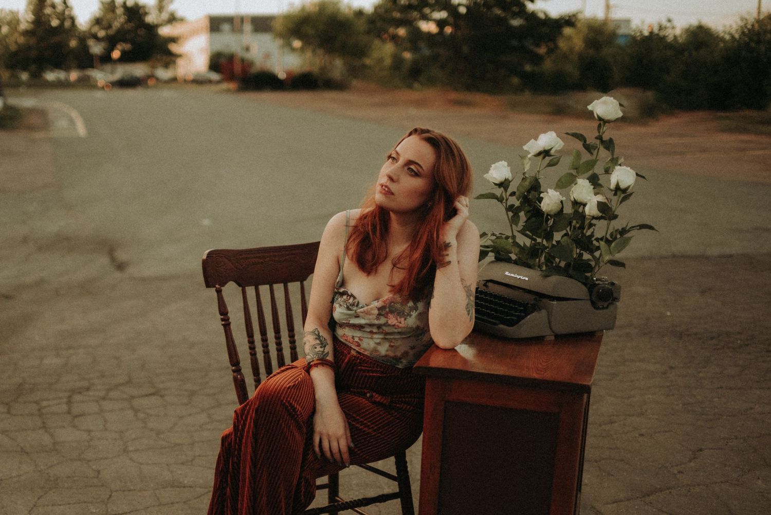 A moody sunset portrait with a rustic wooden table adorned with white flowers on a concrete surface.