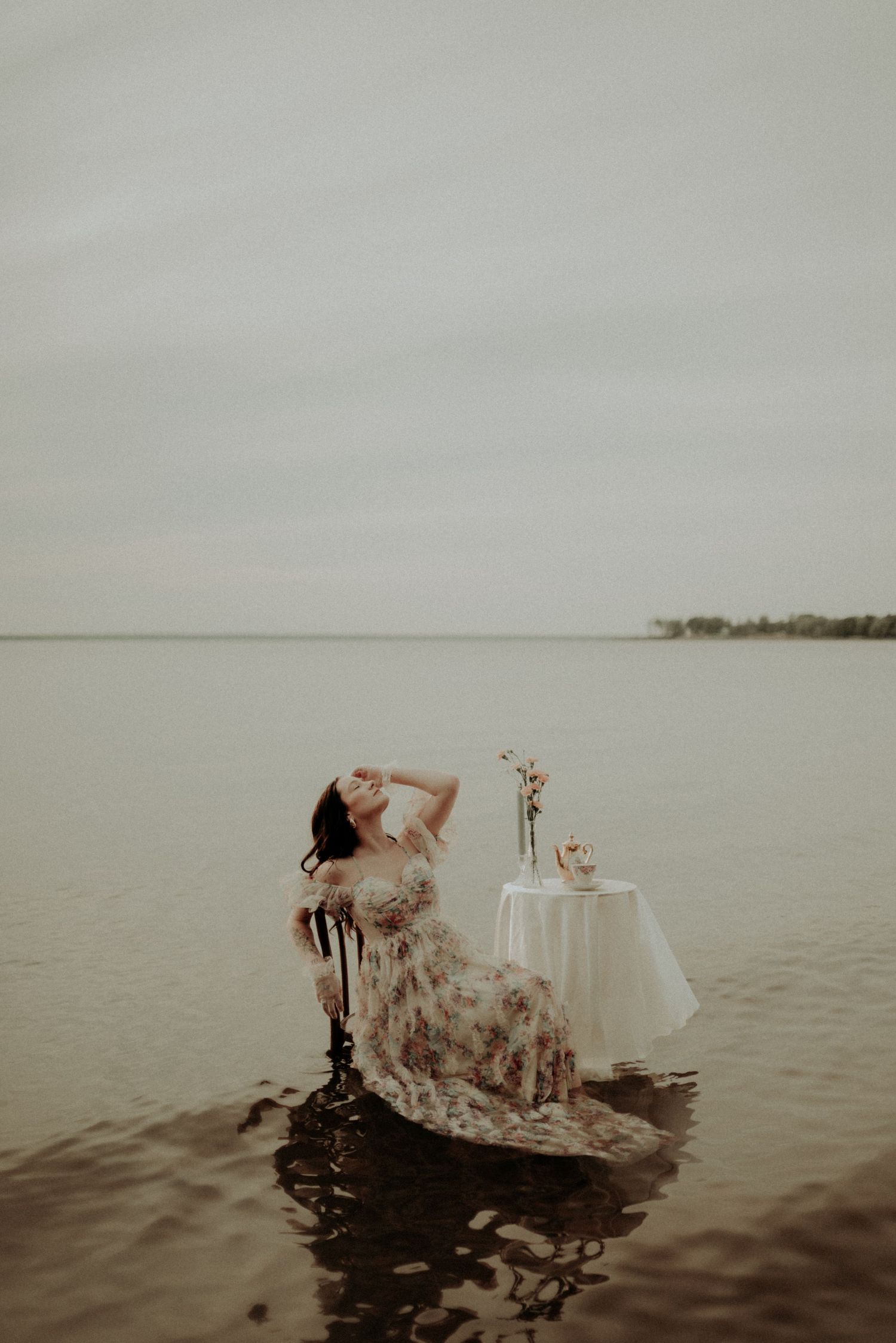 Artistic water portrait with flowing dress, vintage chair and elegant table arrangement.