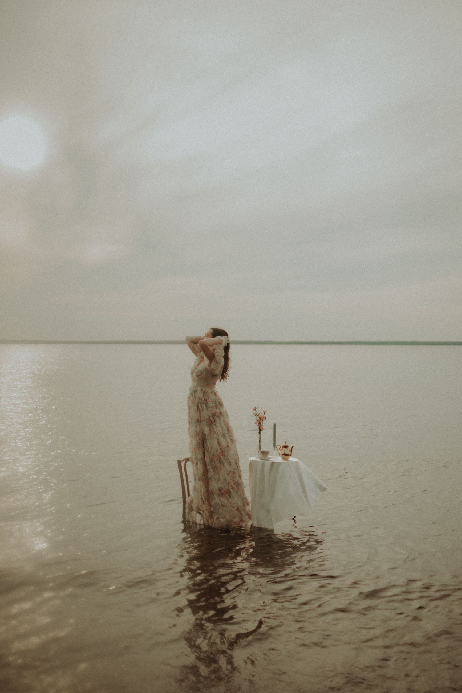 Minimalist water portrait with vintage dress and romantic table setting at dusk.