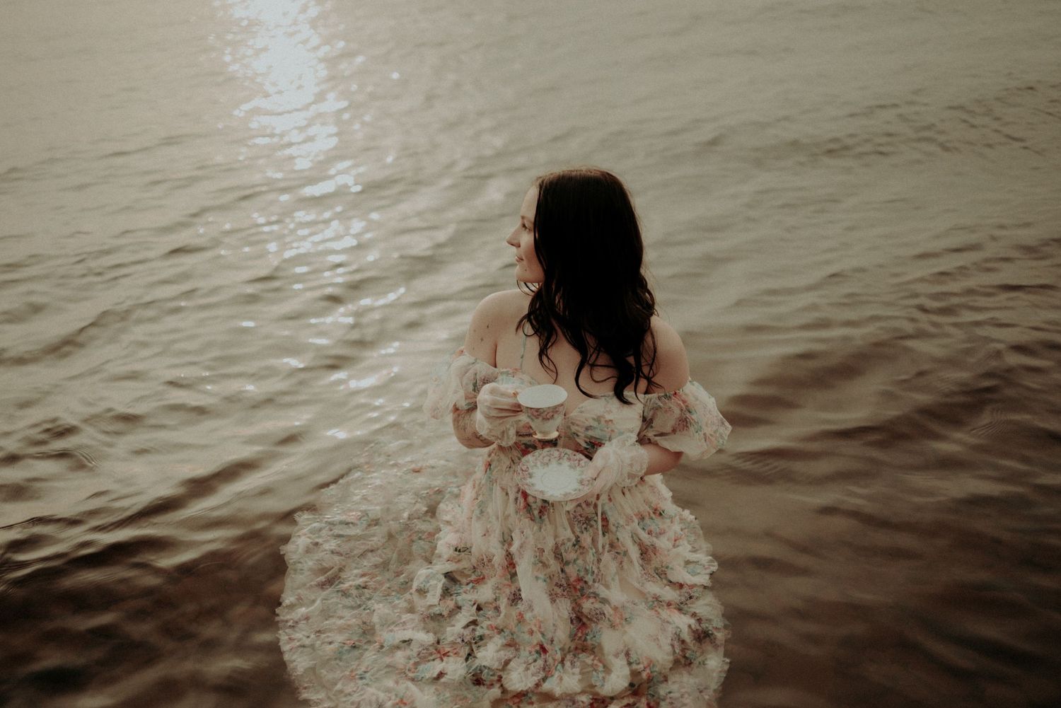 Dramatic water portrait with vintage dress creating ripples in sepia tones.