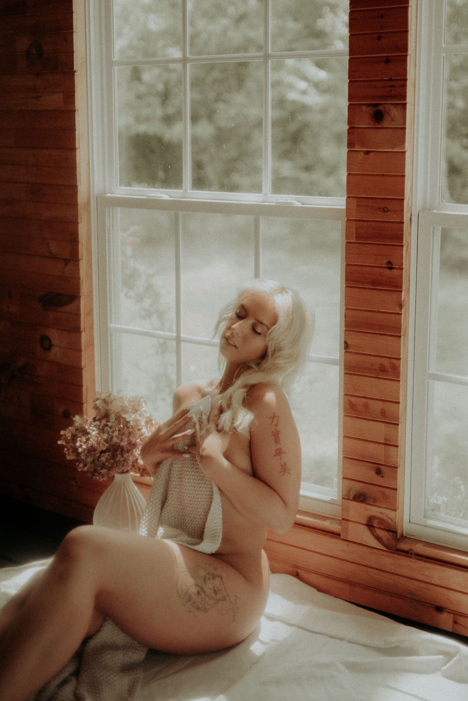 Intimate portrait by sunlit cabin windows with soft natural lighting.