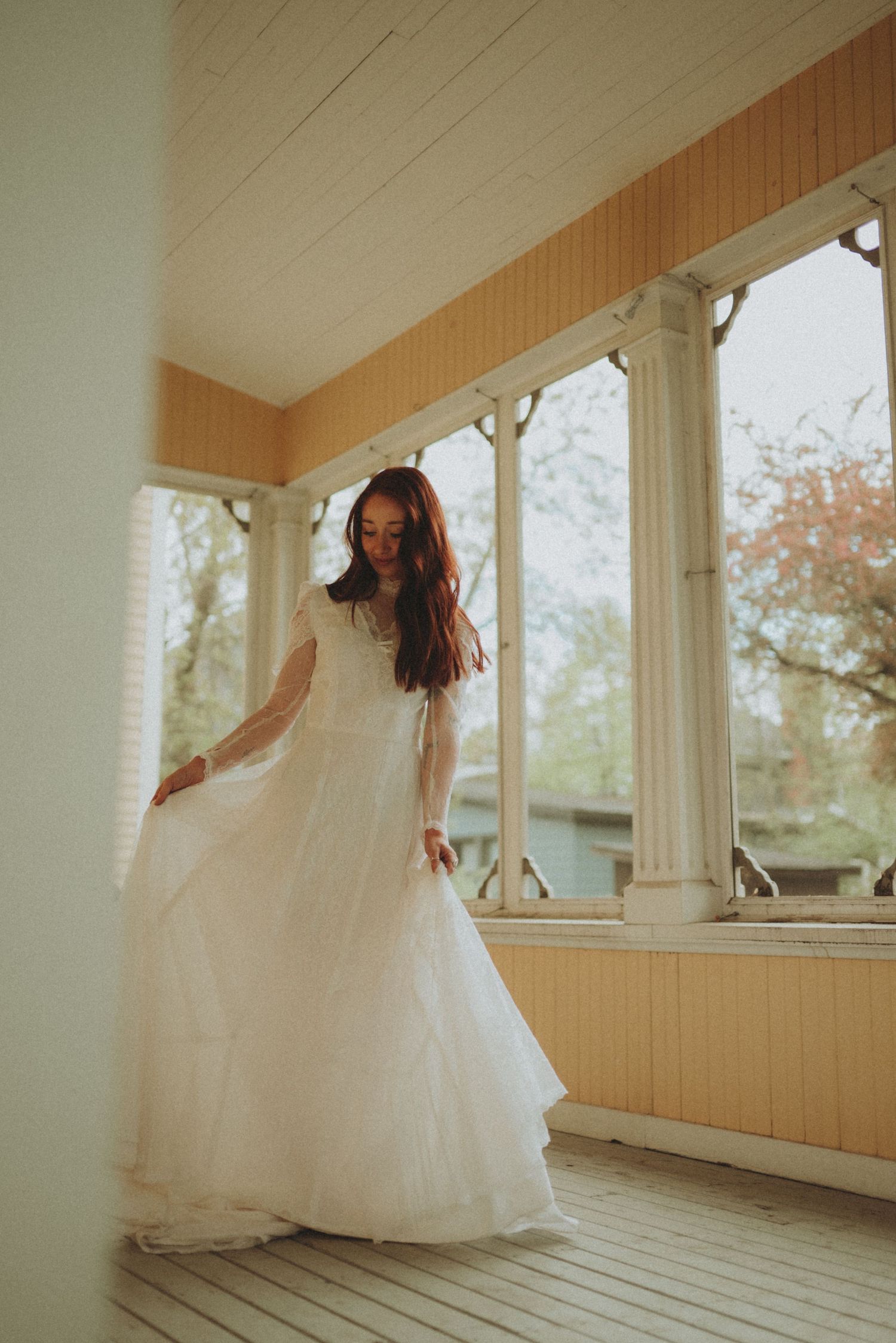 A whimsical bridal portrait capturing movement in a white gown on a classic Victorian porch.