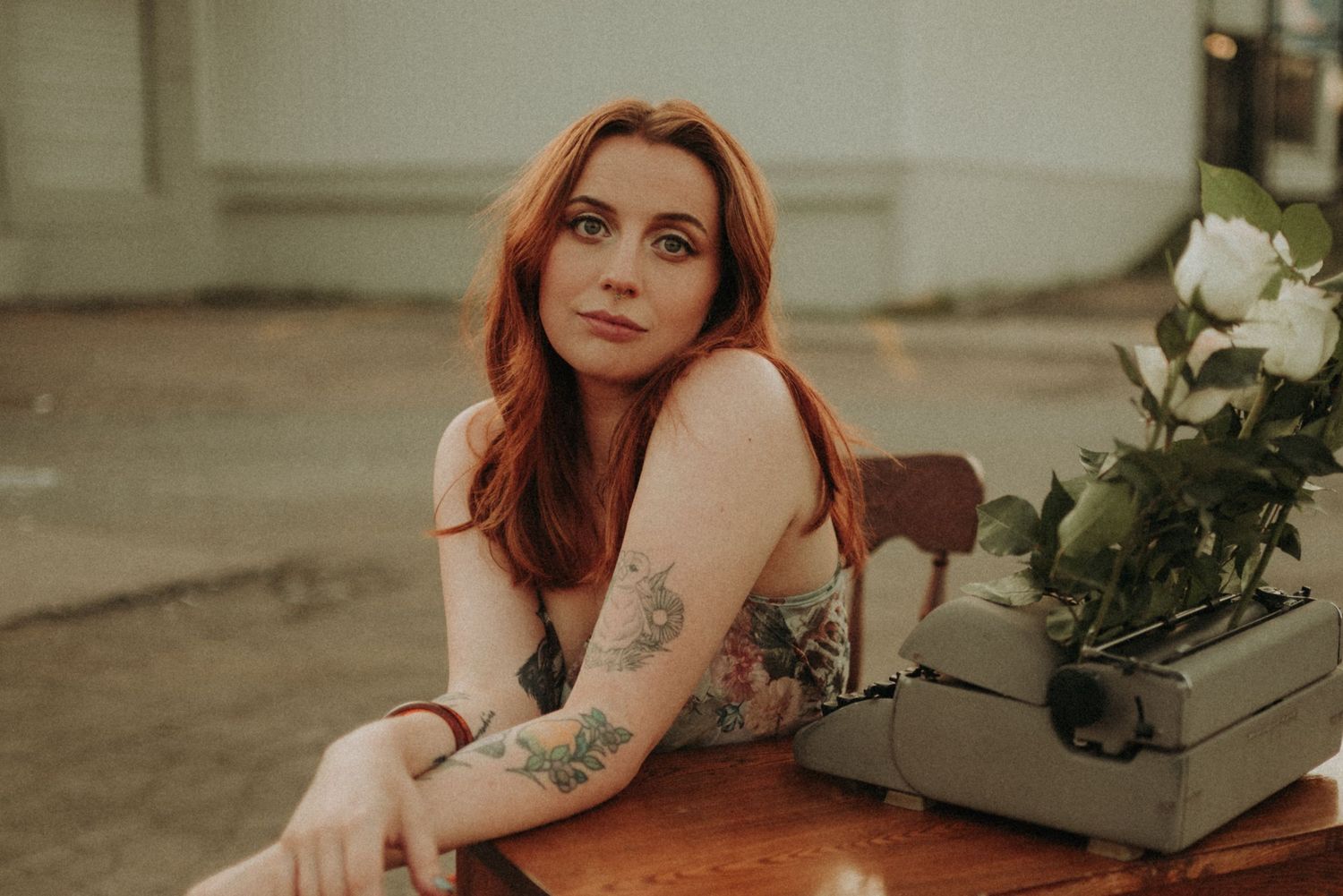 Vintage style portrait with typewriter and flowers on wooden desk in warm lighting.