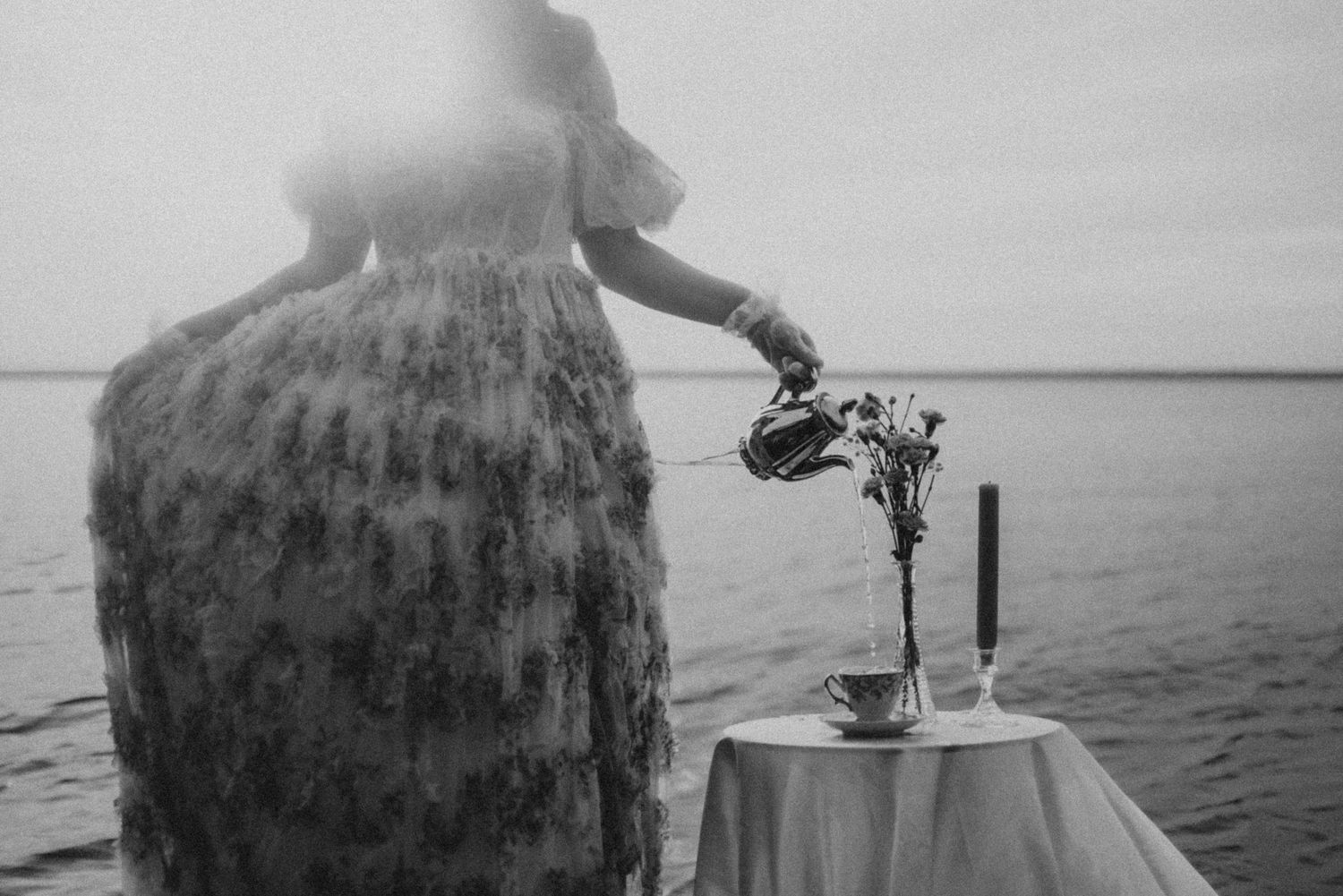 Artistic water photoshoot featuring an antique table setting and flowing dress in muted tones.