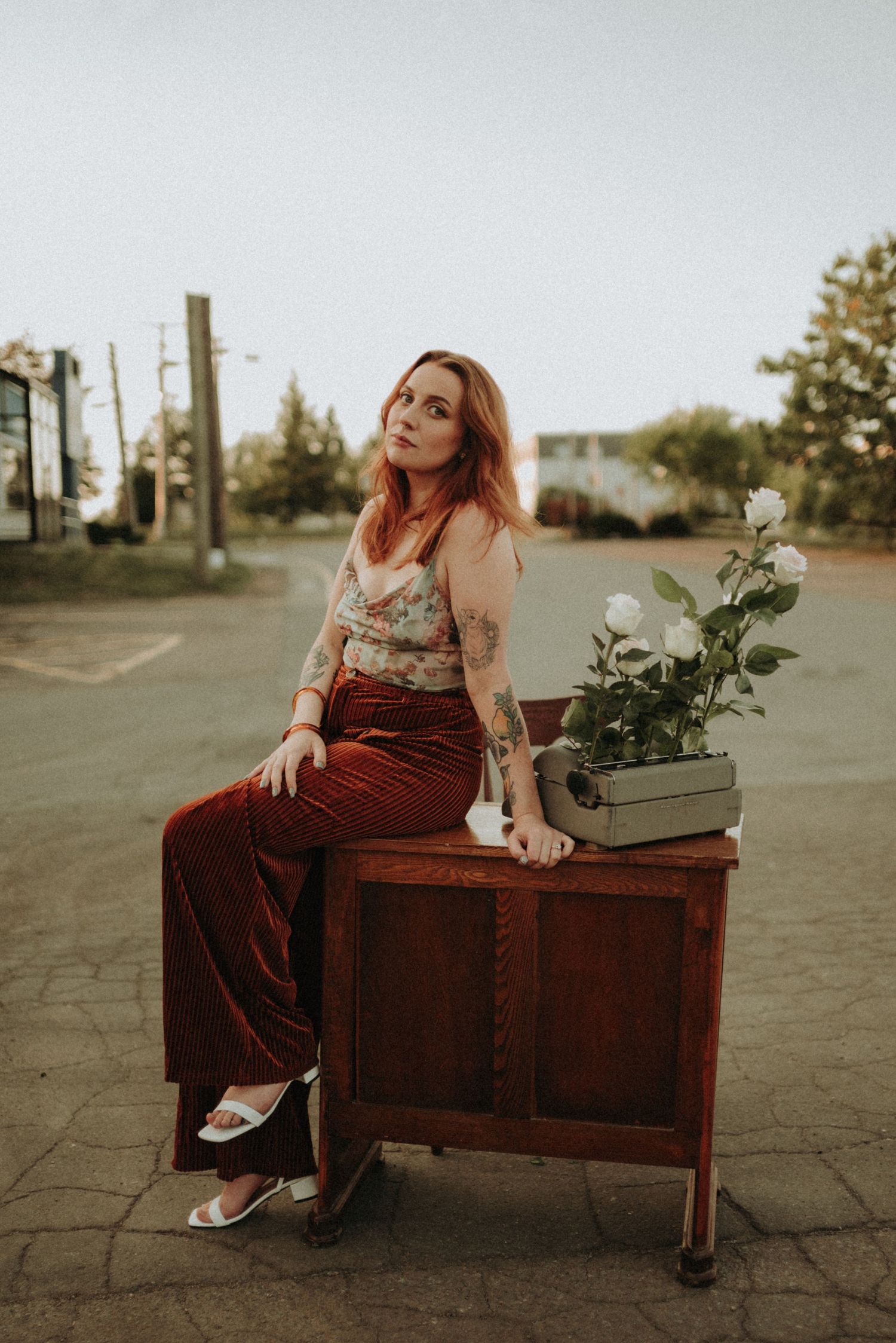 Retro scene with person in burgundy pants seated on wooden furniture with typewriter.