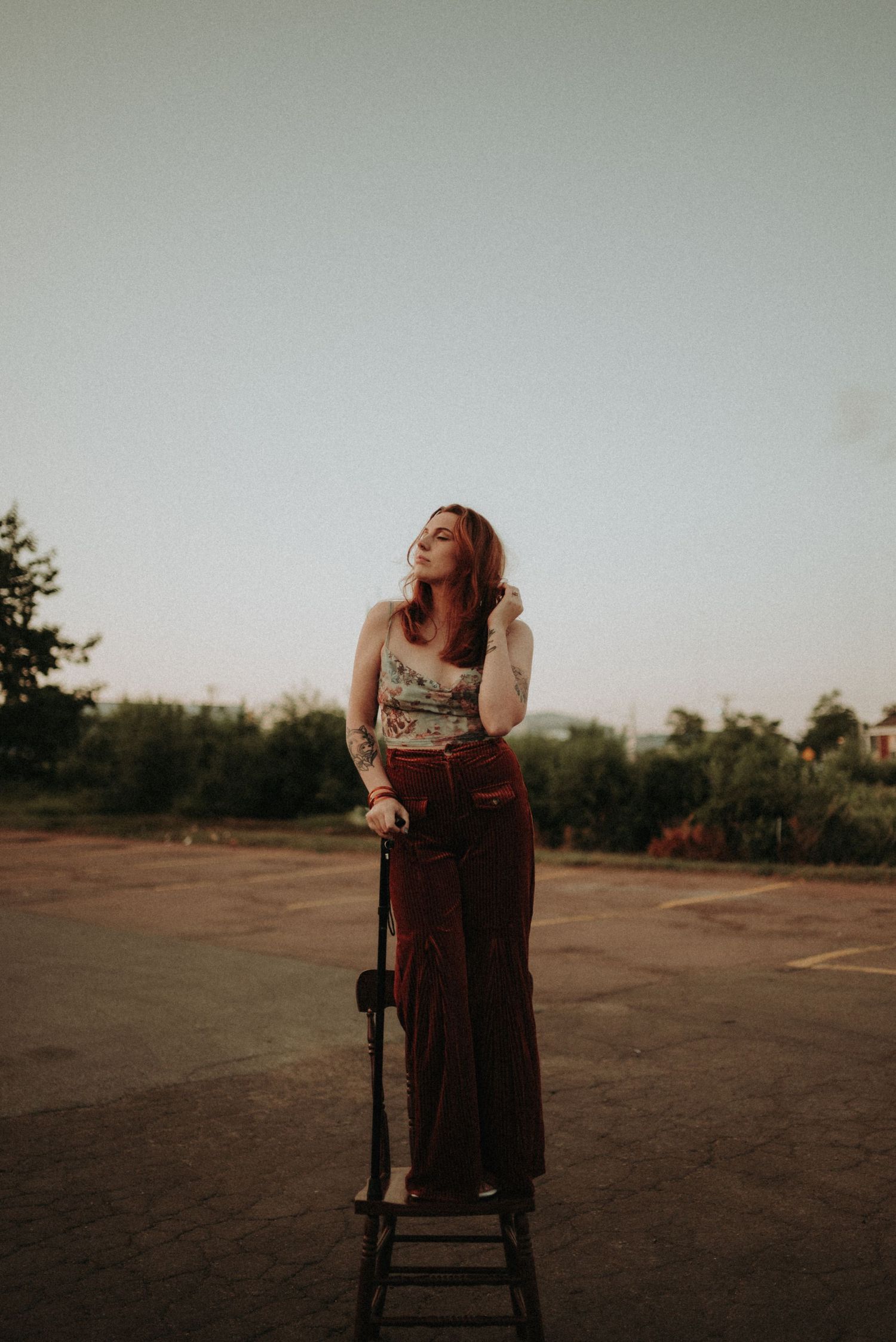 Artistic outdoor portrait on wooden stool at golden hour.