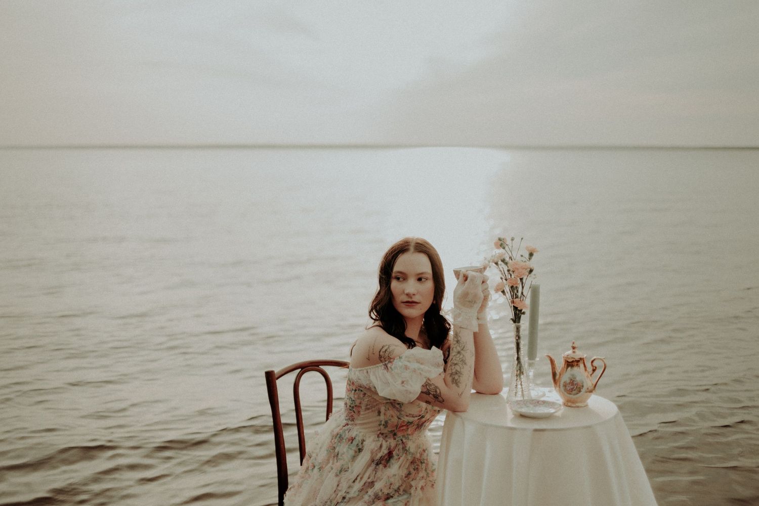 Moody water photoshoot featuring elegant table settings and flowing fabric in sepia tones.