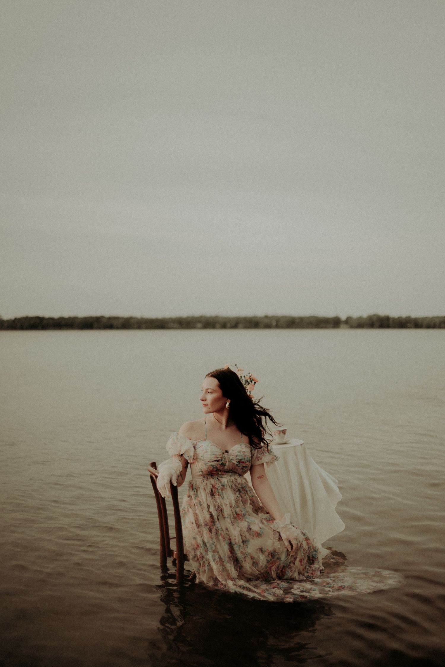 Ethereal water portrait with flowing dress and wind-swept hair in muted tones.