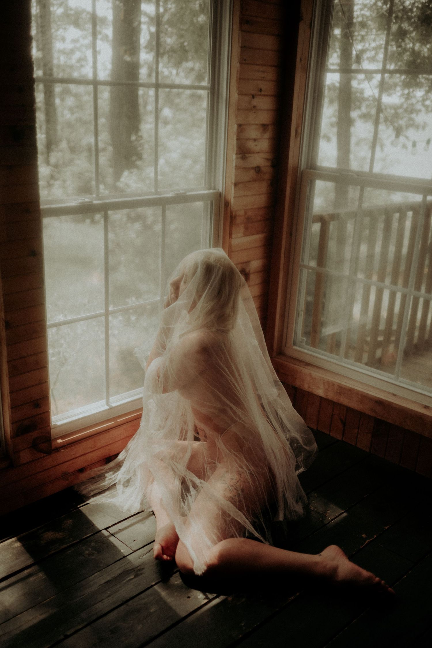 A series of four moody photos showing a figure in white dress by sunlit windows in a rustic wooden room.