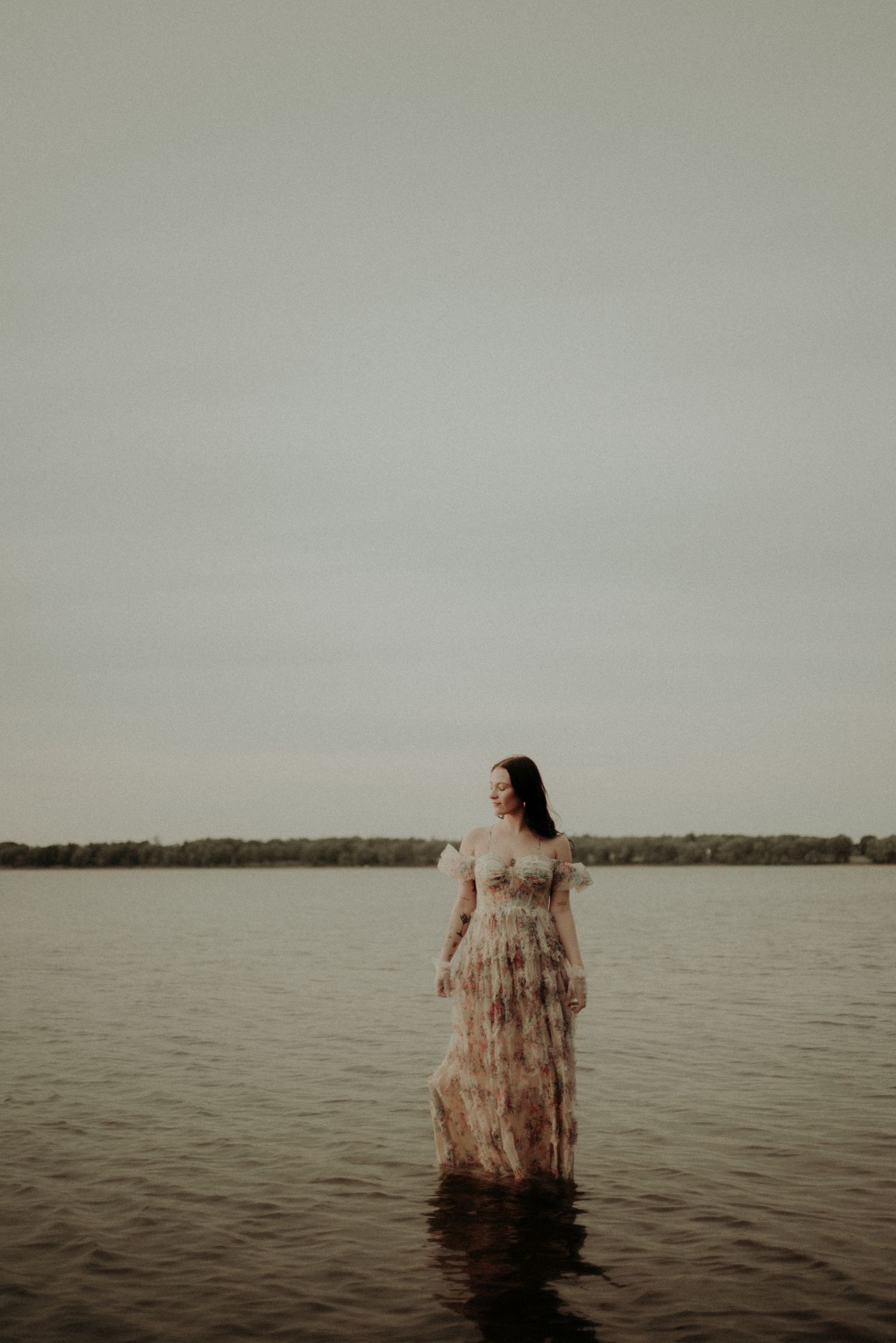 A dramatic full-length portrait in shallow water wearing a layered tulle gown.