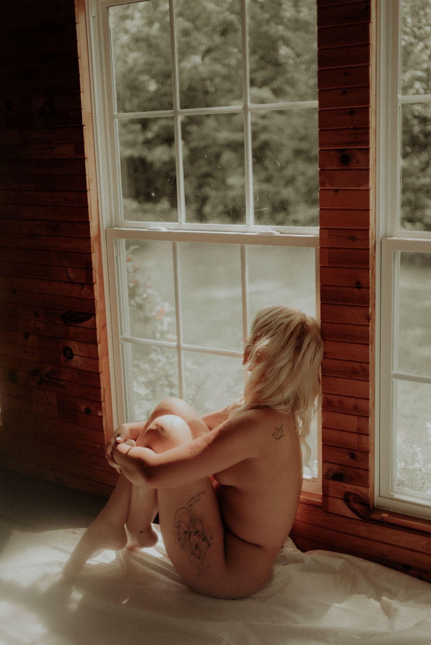 Silhouette against window in intimate artistic portrait with natural lighting.
