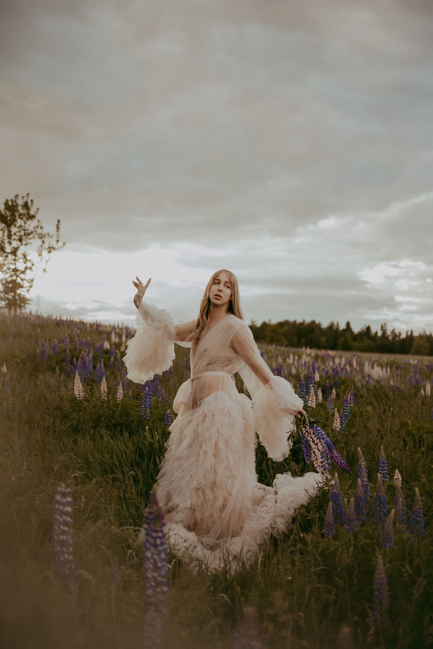 Whimsical dress movement captured in field of lupine flowers at sunset.