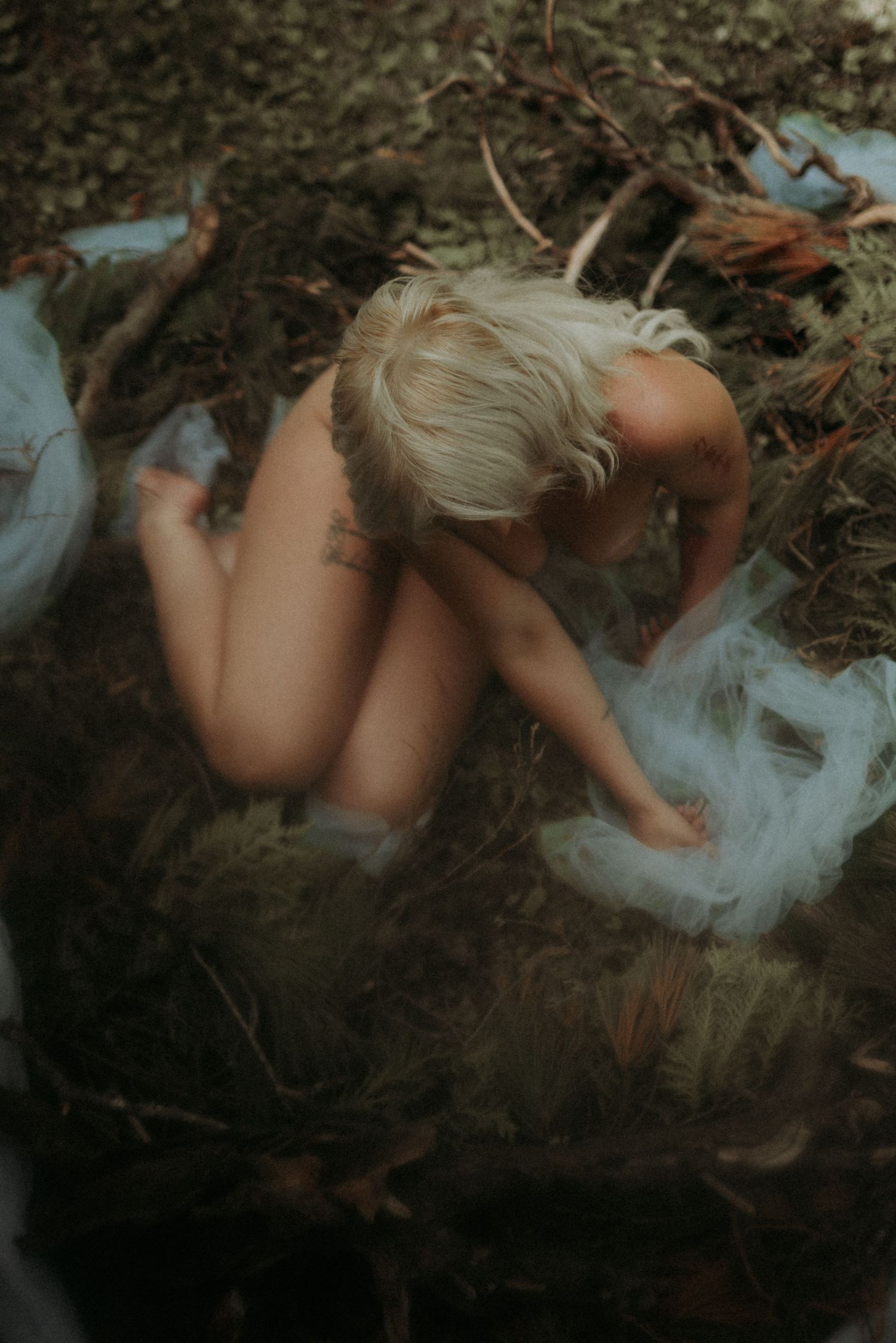 Artistic outdoor portrait among fallen leaves with dreamy, muted color tones.