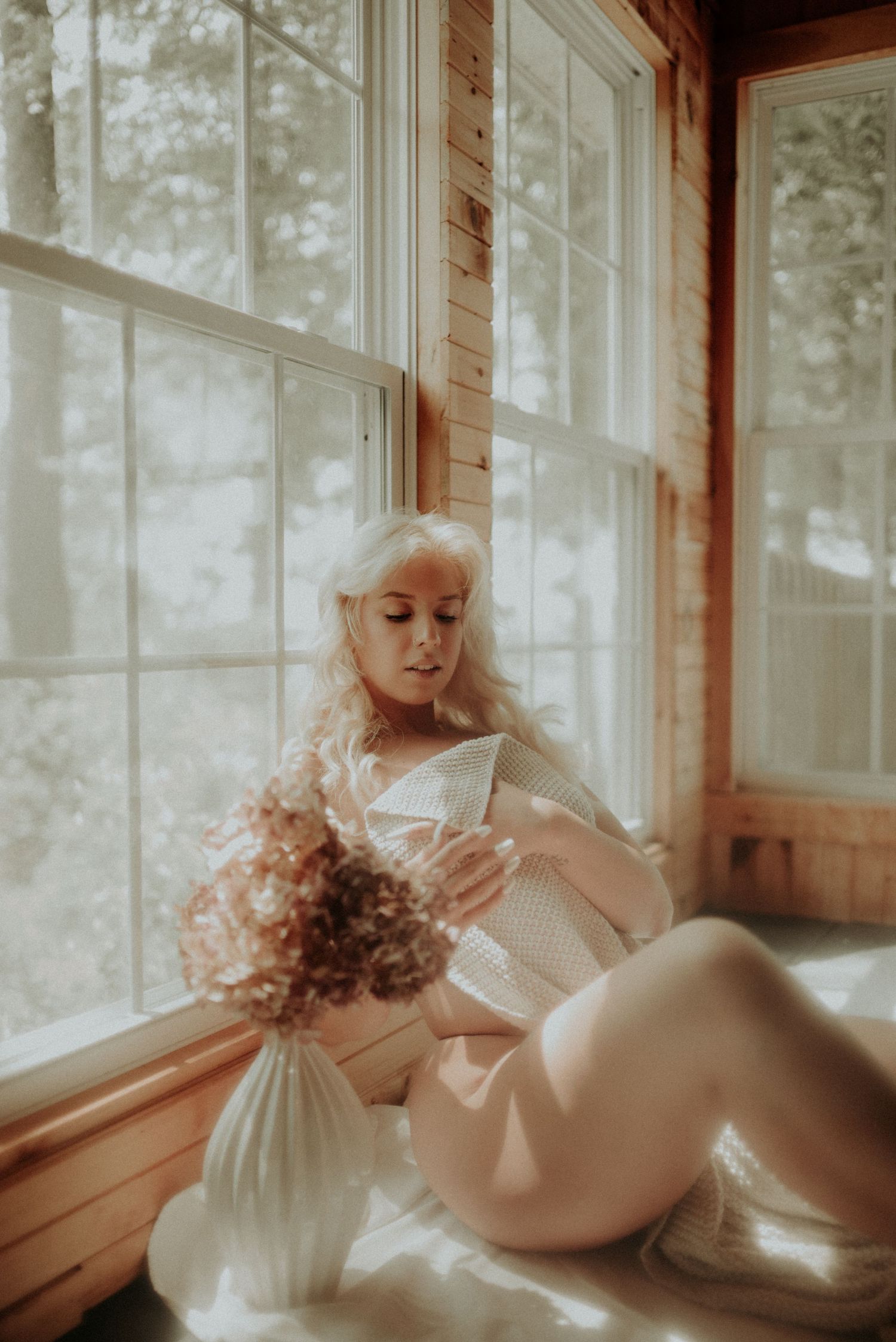Ethereal boudoir photography with delicate lighting through cabin windows.