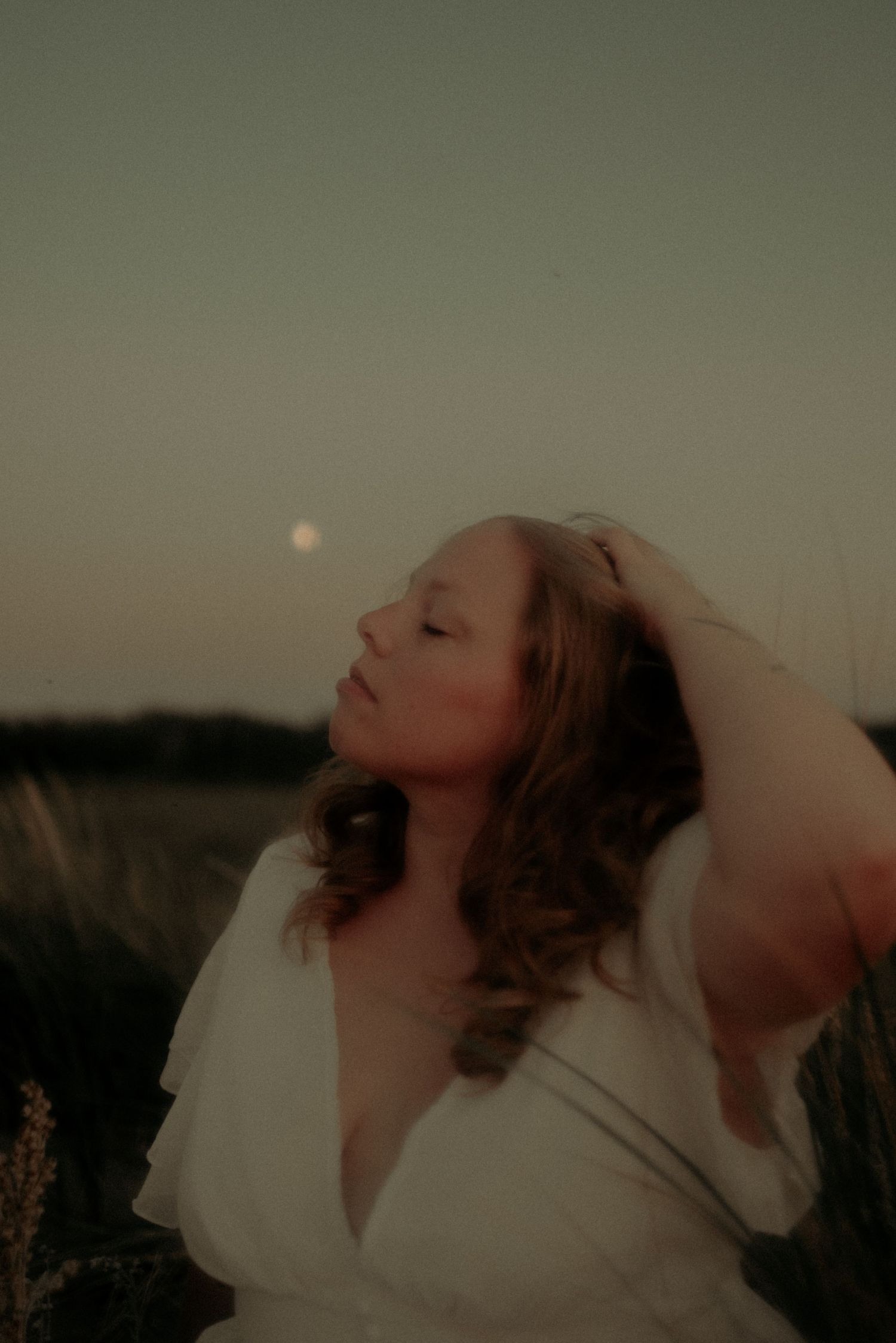 Artistic portrait sequence showing graceful movement in white dress against moody dark background.