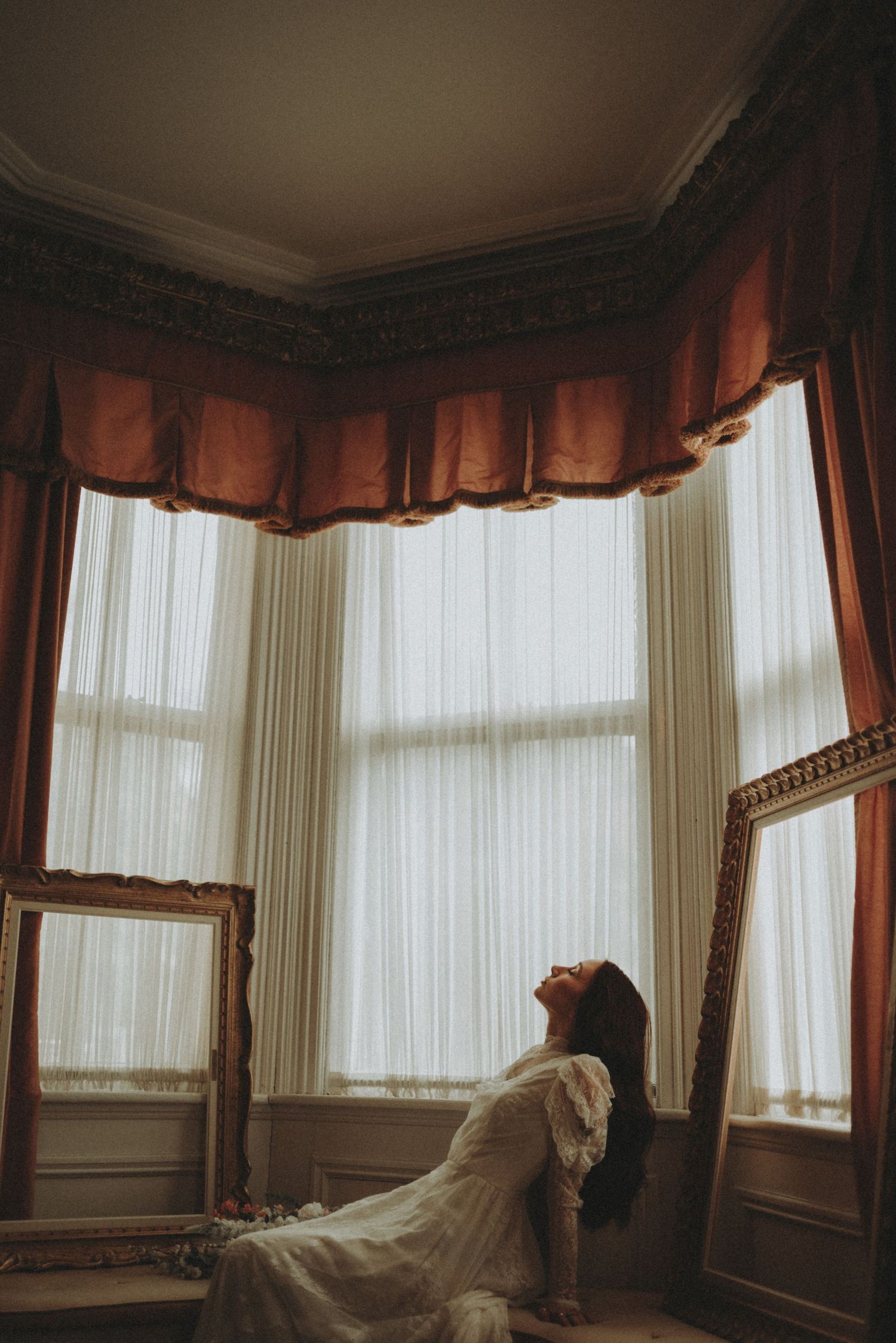Moody cinematic shots of a wedding dress silhouette framed by sheer curtains and window light.