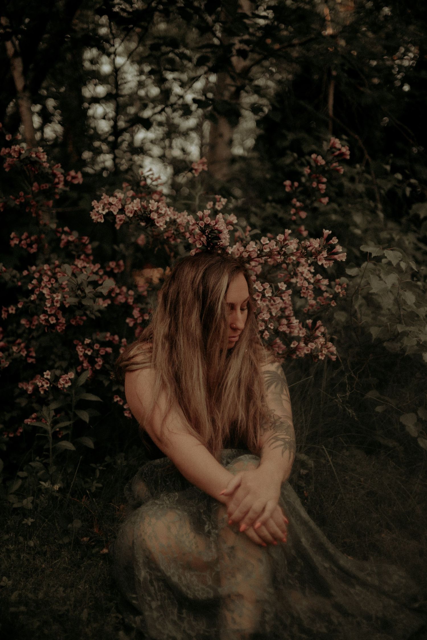 Atmospheric portrait in forest setting with flowering branches and vintage color grading.