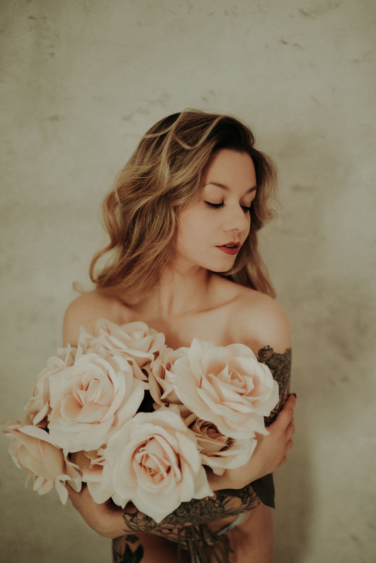 Artistic portrait series featuring soft pink roses and ethereal lighting against a textured neutral wall background.