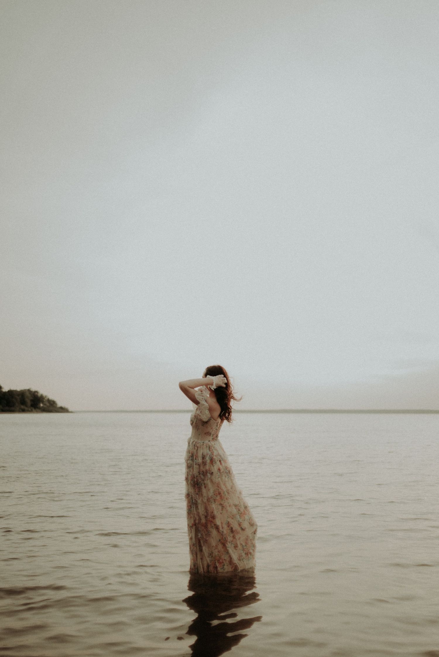 A peaceful pose in calm waters wearing a textured gown against an overcast sky.
